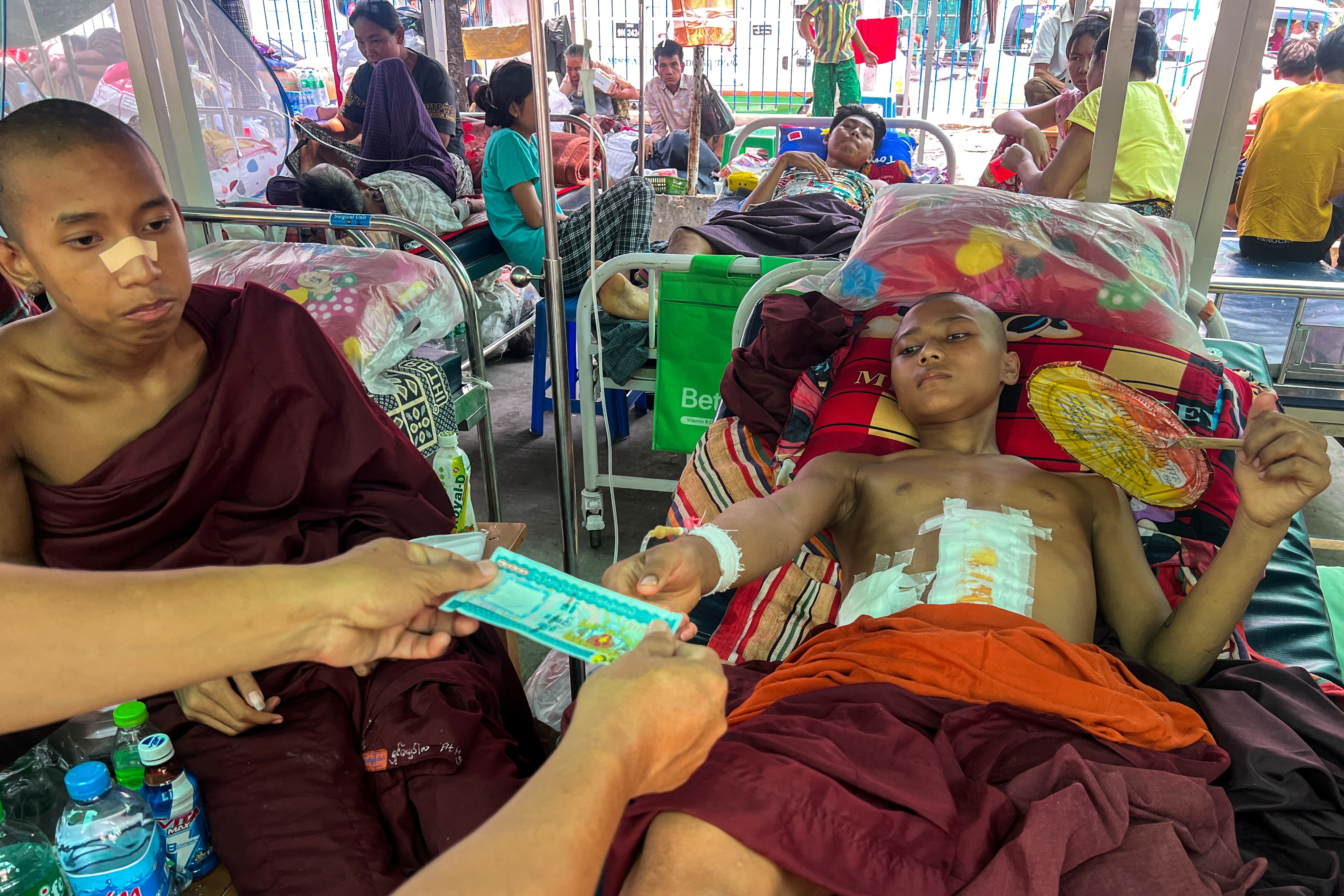 A man donates money to an injured novice at Mandalay General Hospital following a strong earthquake in Mandalay, Myanmar, April 1, 2025. REUTERS/Stringer