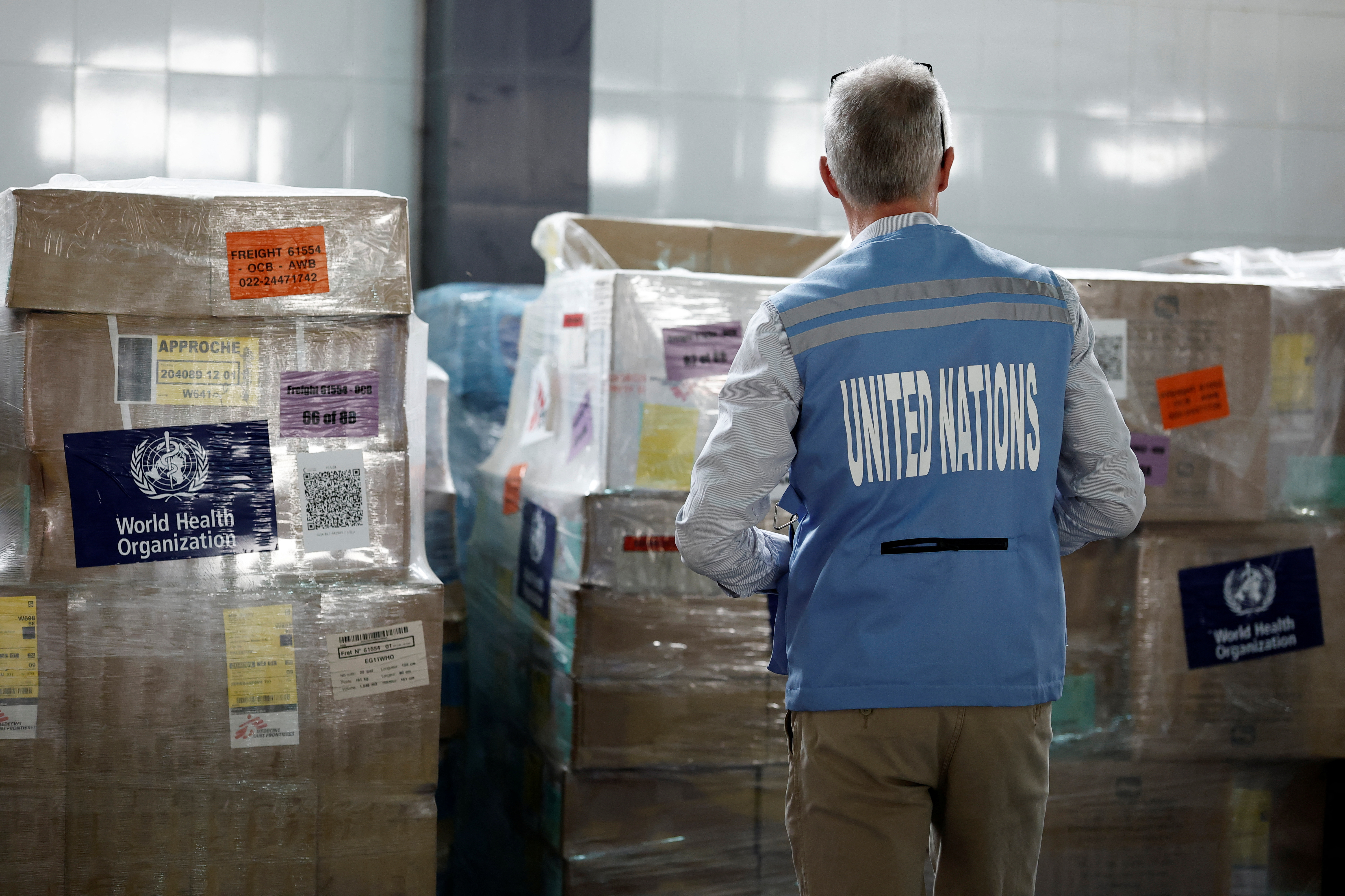 A UN staff member stands in front of humanitarian supplies for Gaza stored at Egyptian Red Crescent warehouses.