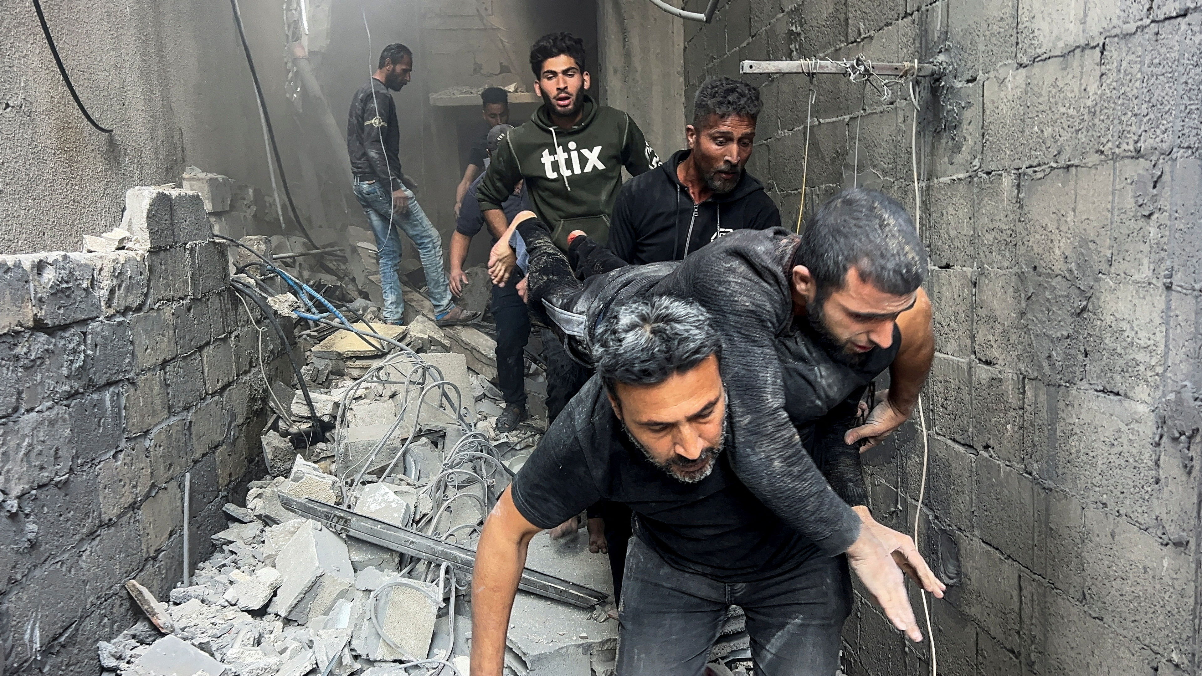Palestinians carry an injured man at the site of an Israeli strike on a house.