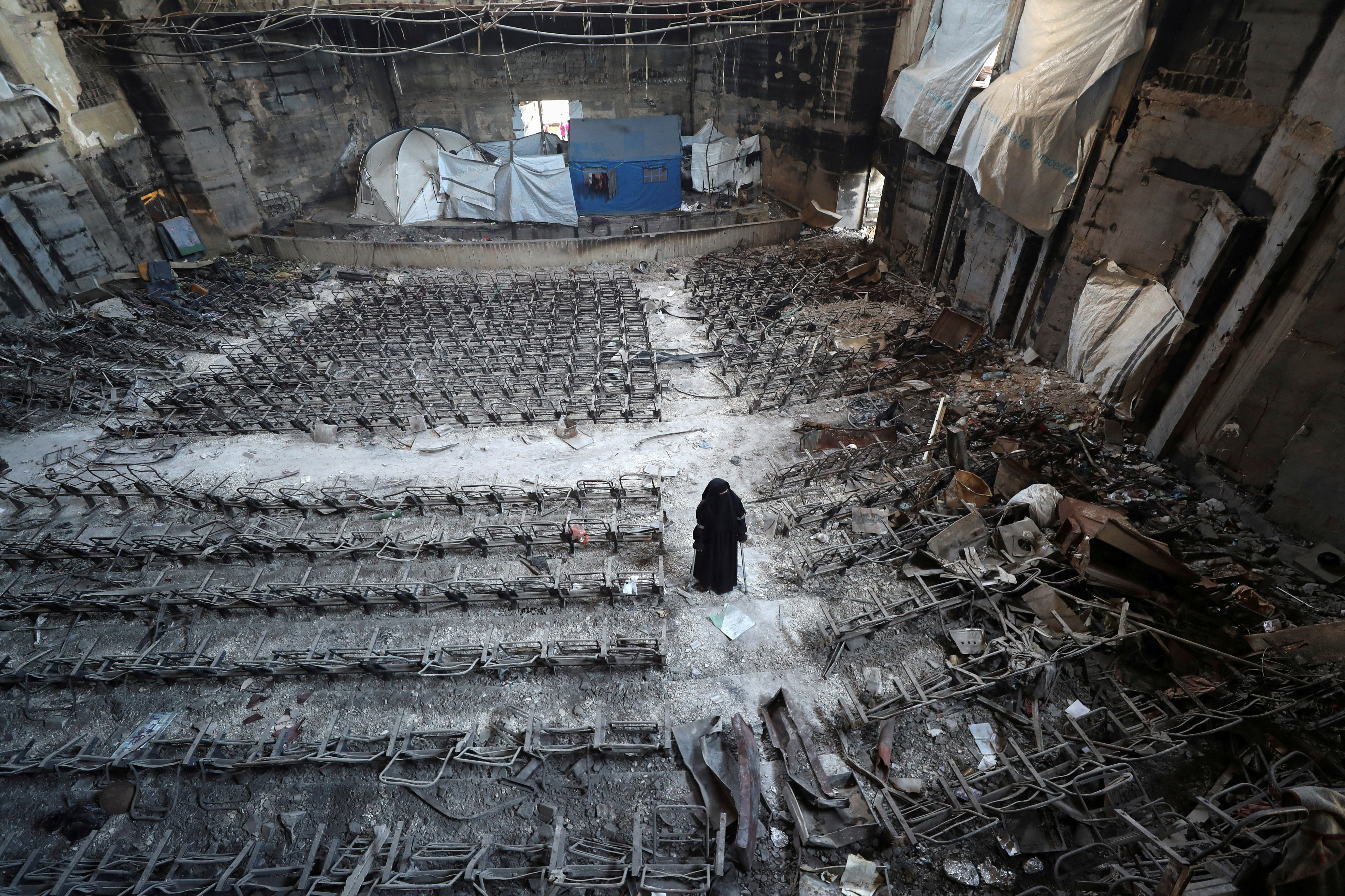 Displaced Palestinian Mervat Al-Bassiouny, whose leg was amputated due to an Israeli strike, views the damage while using crutches as she shelters inside a building at the Islamic University of Gaza, from where she graduated and which was hit in previous Israeli strikes, in Gaza City April 11, 2025. REUTERS/Mahmoud Issa/File Photo
