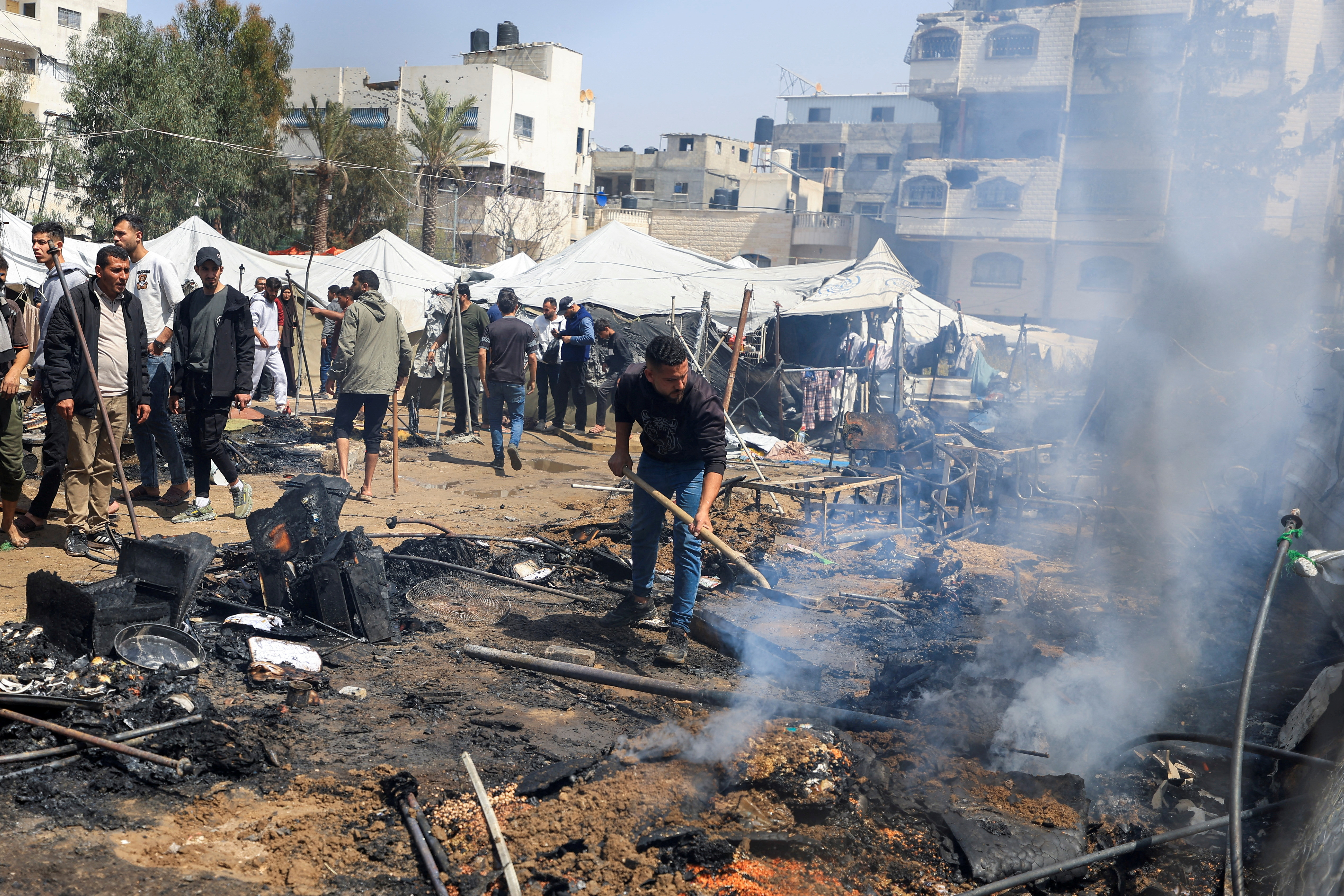Palestinians inspect the site of an Israeli strike on a tent camp sheltering displaced people in Gaza City