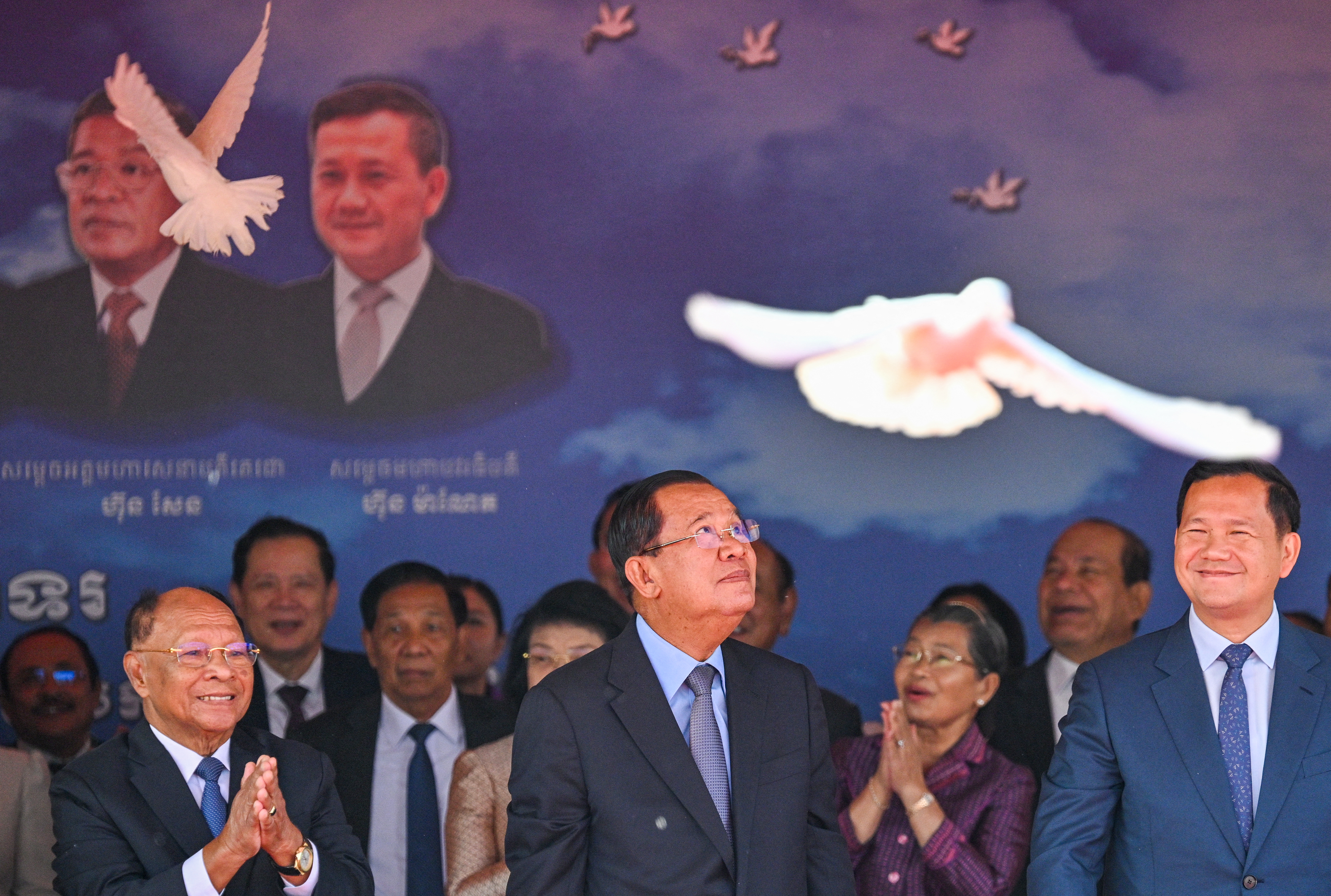 Cambodia's Senate President Hun Sen (C), Cambodia's Prime Minister Hun Manet (R) and Honorary President of the Cambodian People's Party (CPP) Heng Samrin (L) release doves during a ceremony marking the 46th anniversary of the fall of the Khmer Rouge regime in Phnom Penh on January 7, 2025. (Photo by TANG CHHIN SOTHY / AFP)