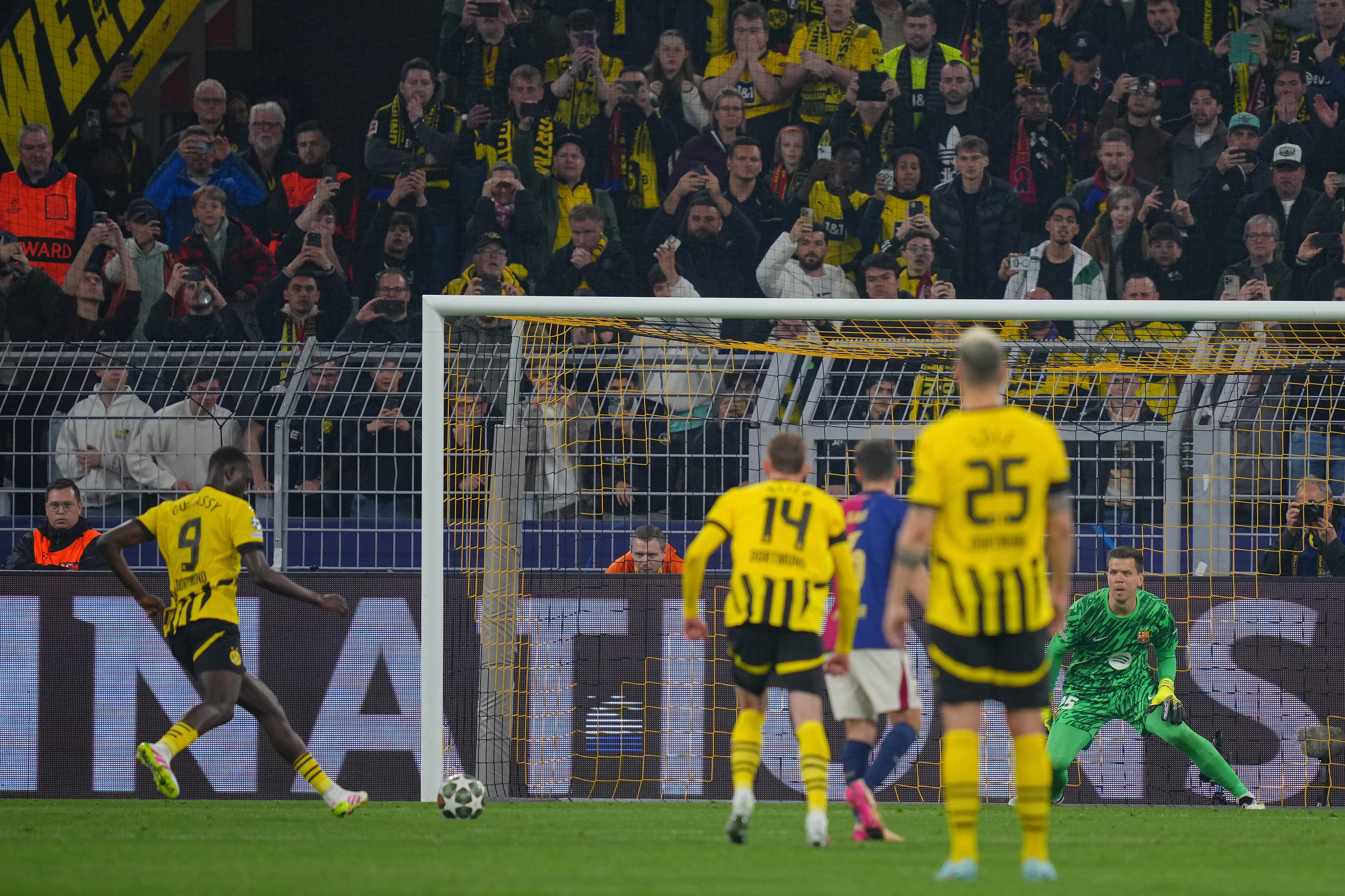 Dortmund's Guinean forward #09 Serhou Guirassy (L) scores the opening goal from the penalty spot past Barcelona's Polish goalkeeper #25 Wojciech Szczesny during the UEFA Champions League quarter-final second leg football match between BVB Borussia Dortmund and FC Barcelona in Dortmund, western Germany on April 15, 2025. (Photo by Pau BARRENA / AFP)