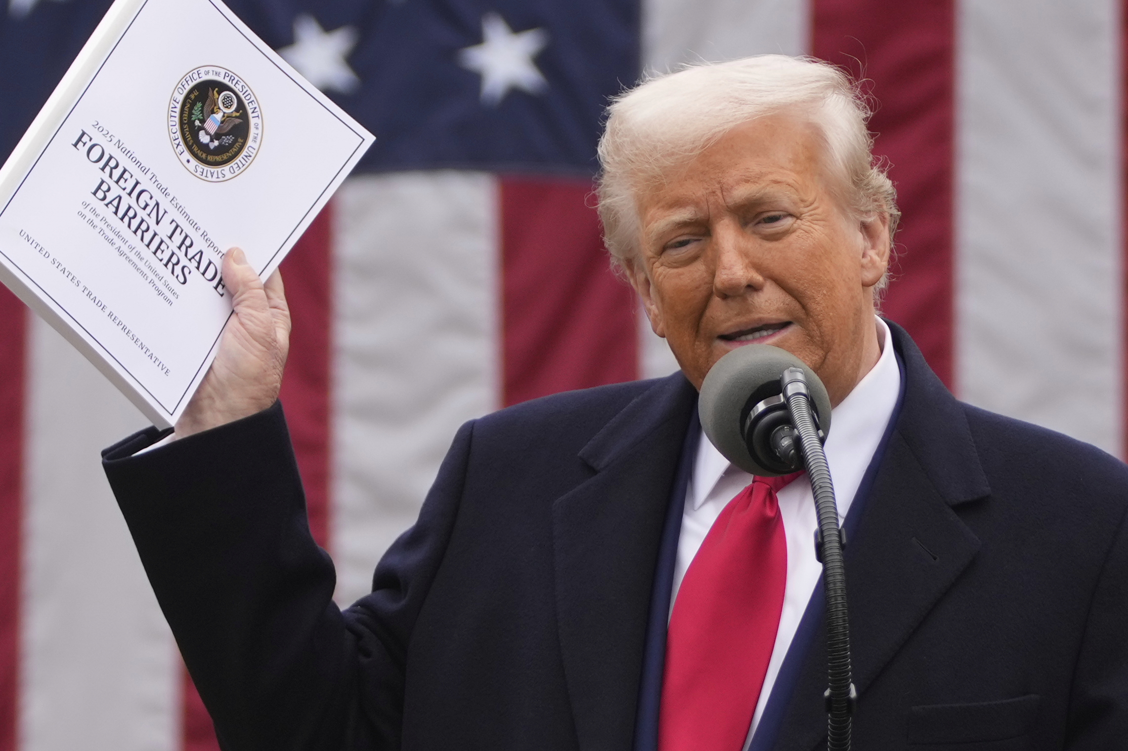 Donald Trump holds up an executive order on tariffs.