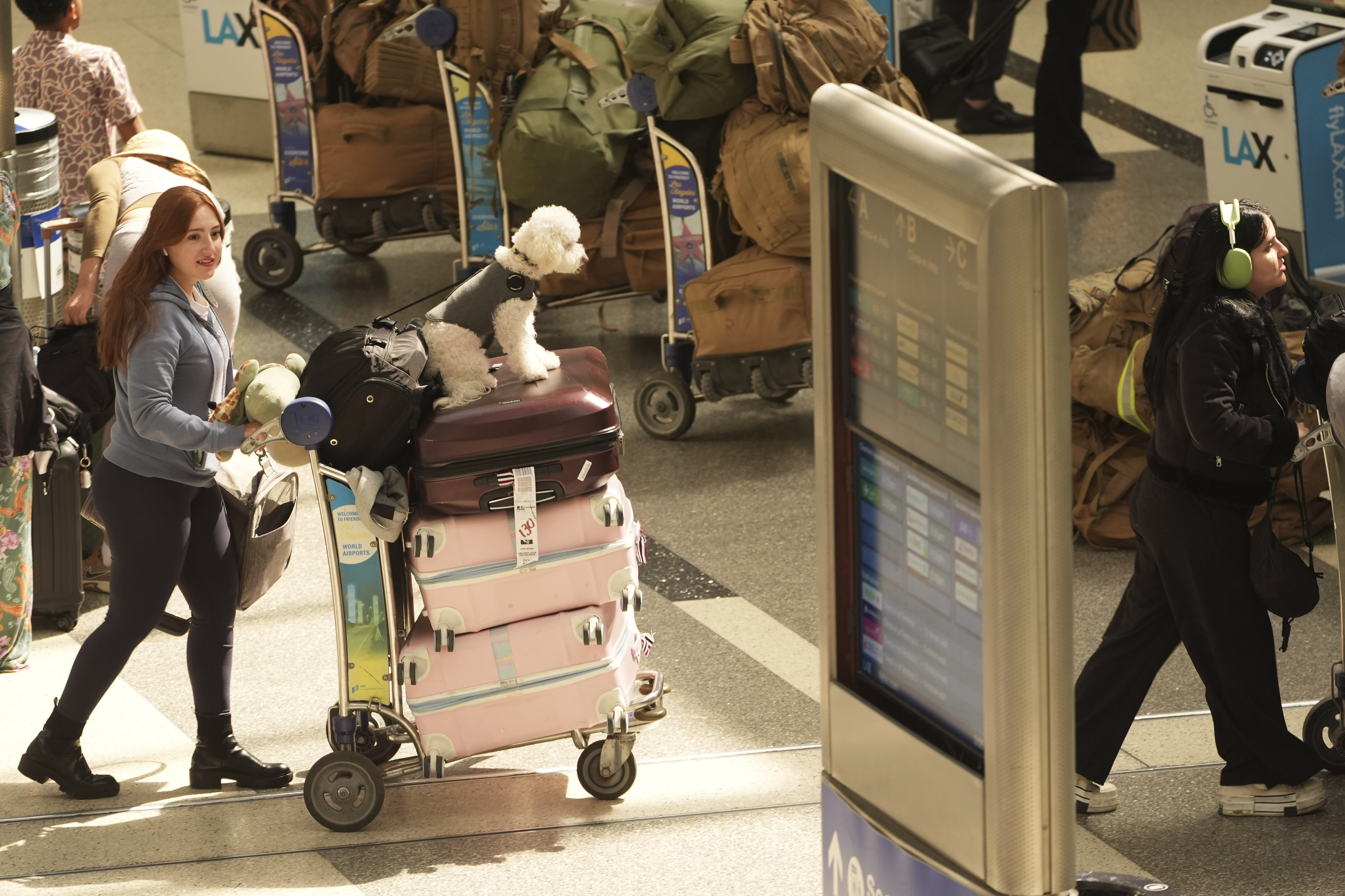 Travellers push carts of luggage through LAX.