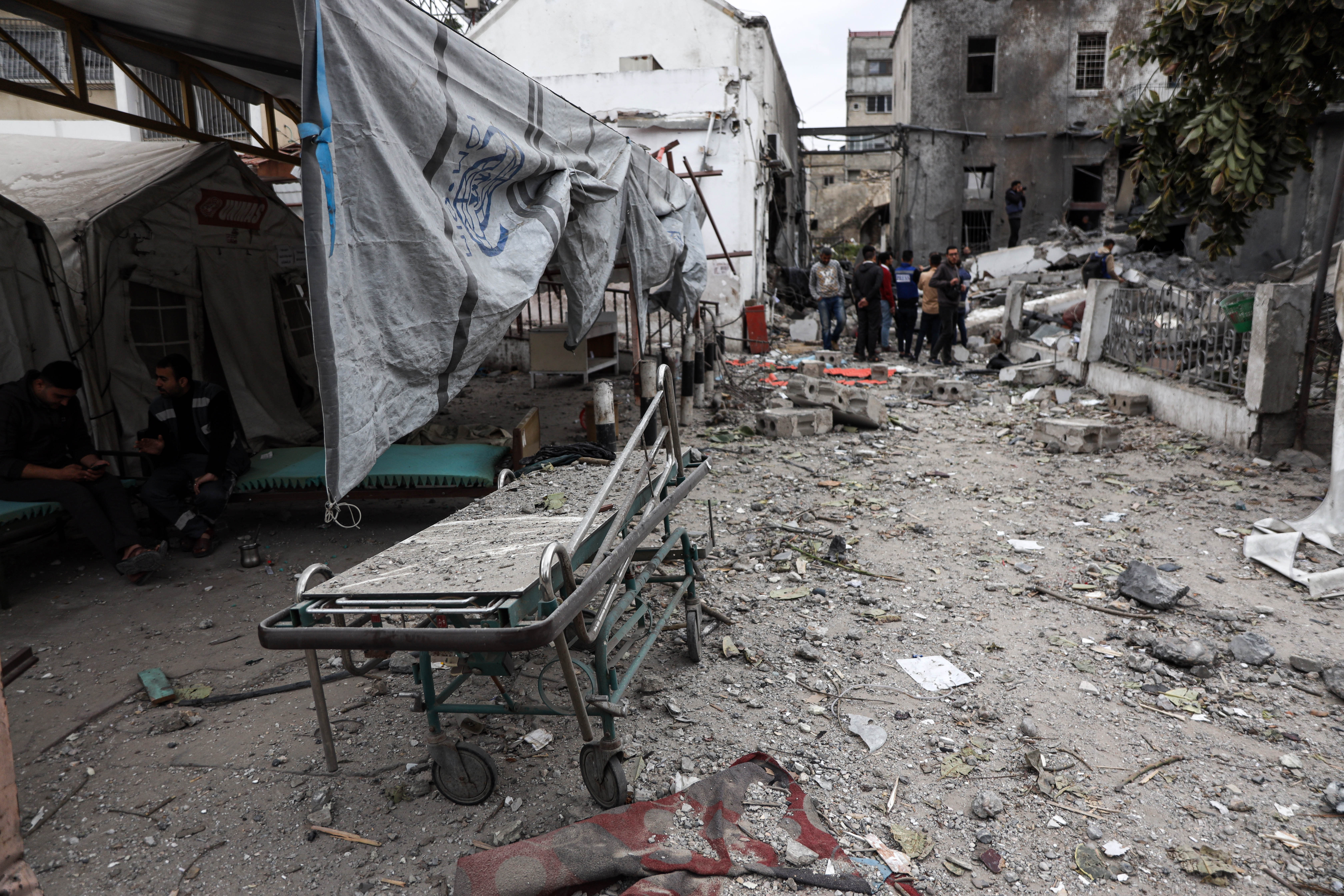In the rubble a gurney, a blanket, some small bits of medical equipment, to the left are the tent wards, damaged