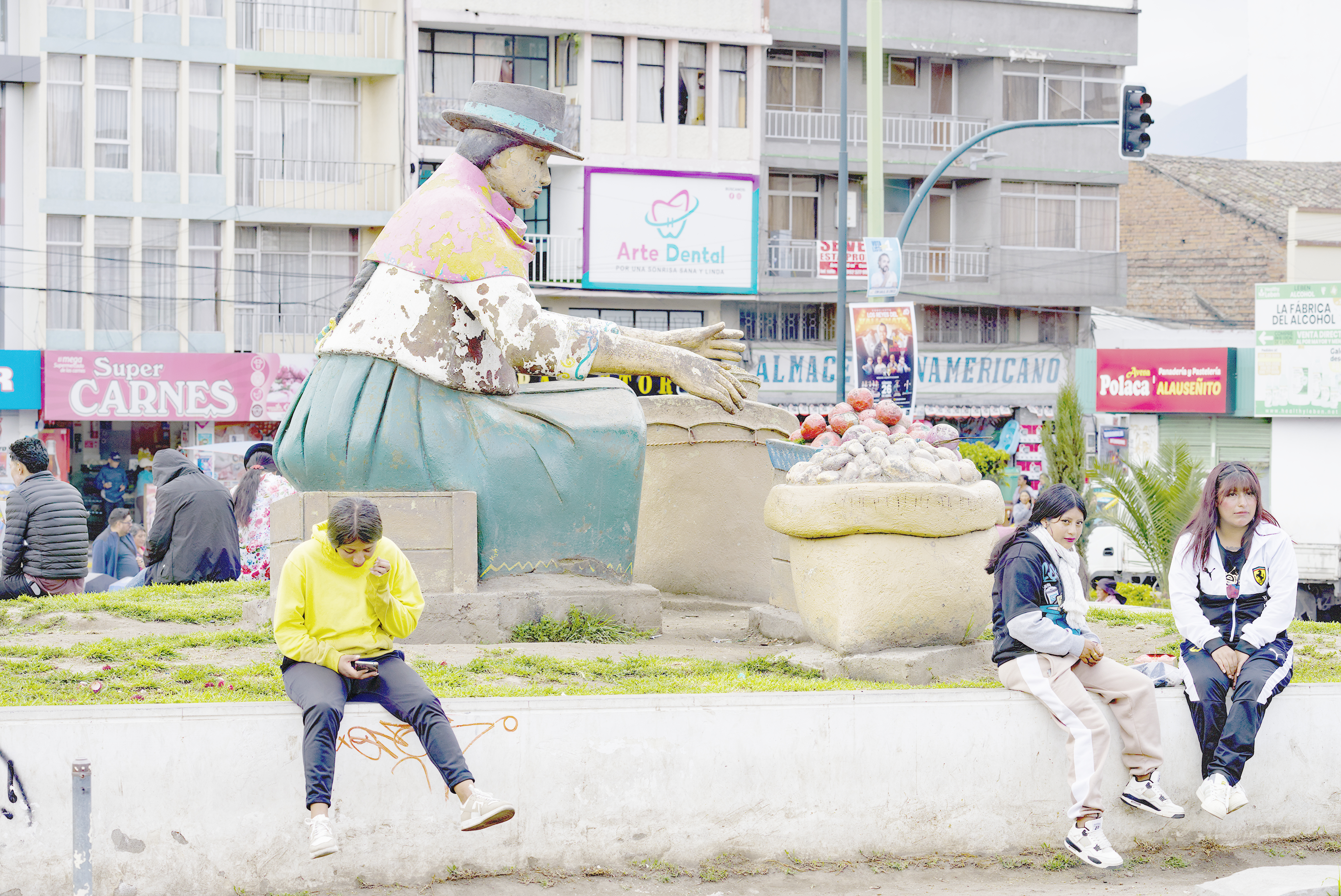 People sit around a statue of an Indigenous woman in Latacunga, Ecuador