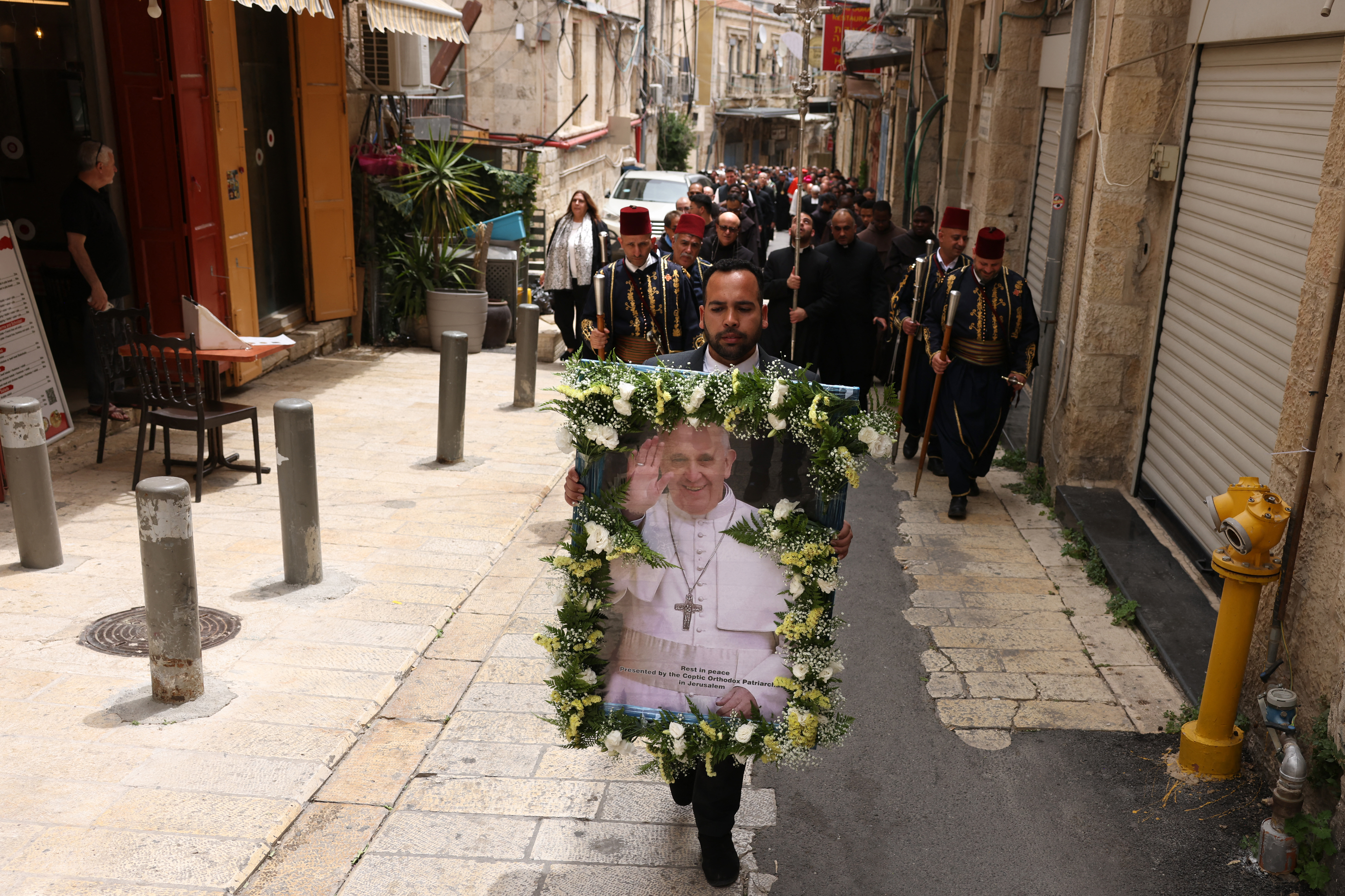 A Catholic Christian holds up a portrait of Pope Francis during a procession in Jerusalem's old city ahead of a memorial mass for the late pontiff at the Church of the Holy Sepulchre in Jerusalem on April 23, 2025.