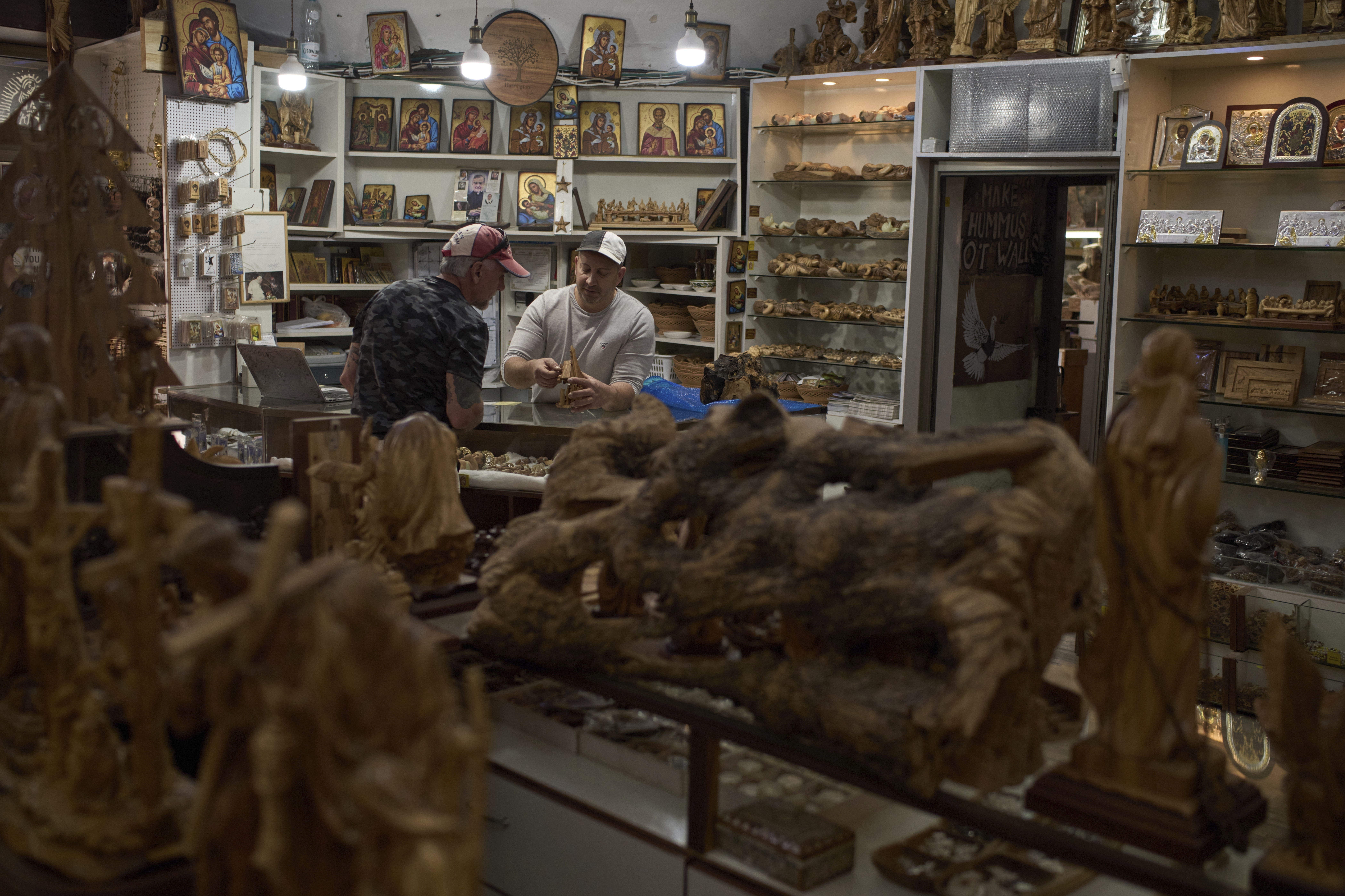 Bassem Giacaman, right, sells one of his olive-wood products to a tourist who visited his gift shop prior to Holy Week celebrations in the West Bank city of Bethlehem on Wednesday, April 9, 2025. (AP Photo/Leo Correa)