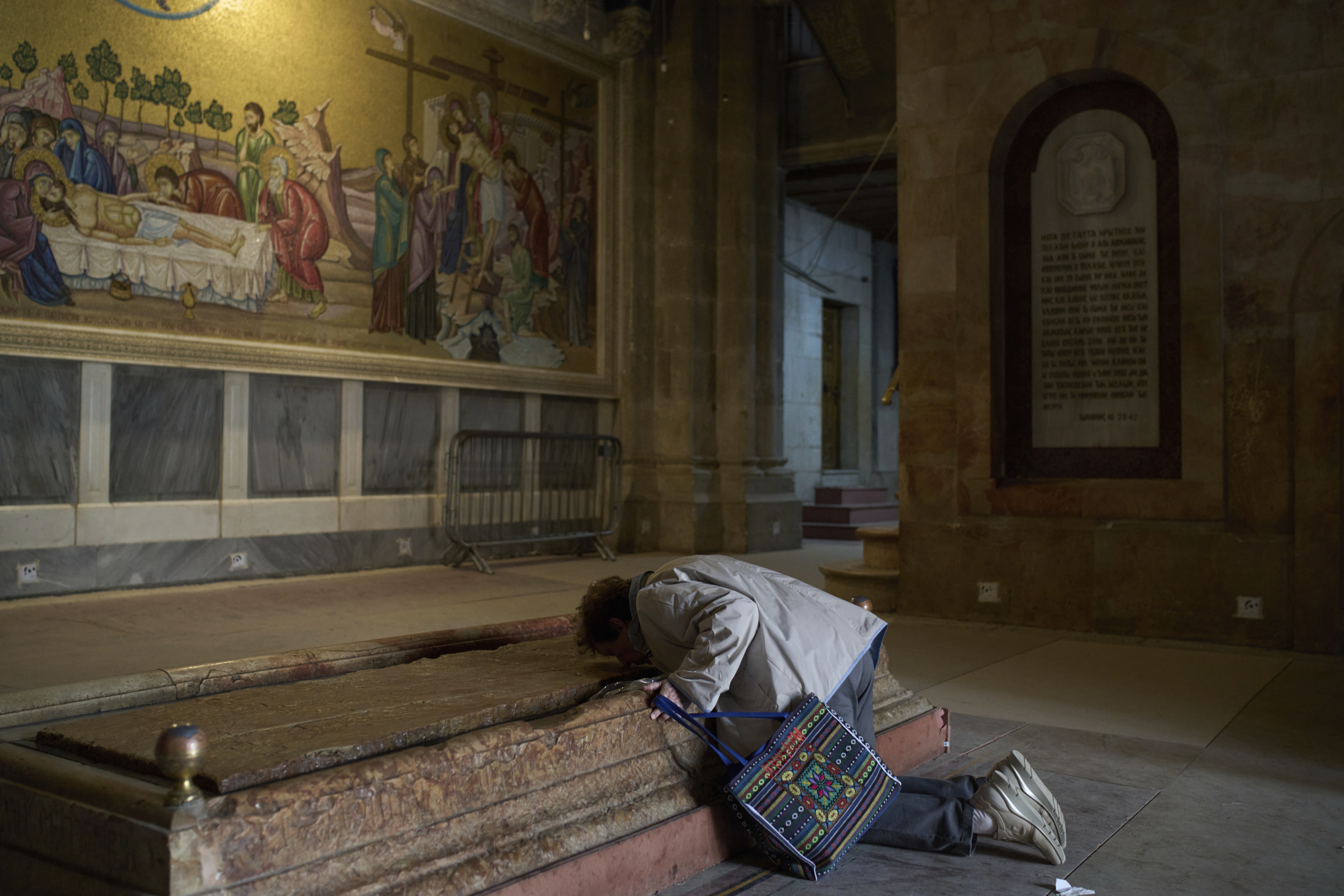 A woman kisses the Stone of Unction, which is traditionally claimed as the stone where Jesus' body was prepared for burial, at the Church of the Holy Sepulchre, where many Christians believe Jesus was crucified, buried and rose from the dead, prior to Holy Week celebrations in the Old City of Jerusalem on Wednesday, April 9, 2025. (AP Photo/Leo Correa)
