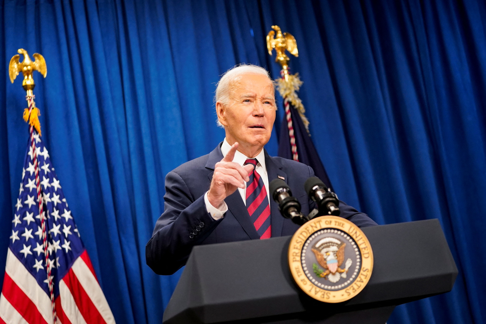 Joe Biden stands behind a podium and speaks.