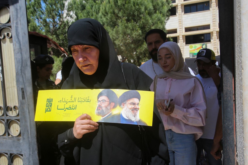 A woman holds a flyer with portraits of slain Hezbollah leaders Hassan Nasrallah (R) and successor Hashem Safieddine (L) at a polling station in the municipal elections in Nabatieh in southern Lebanon on May 24, 2025. [Mahmoud Zayyat/AFP]