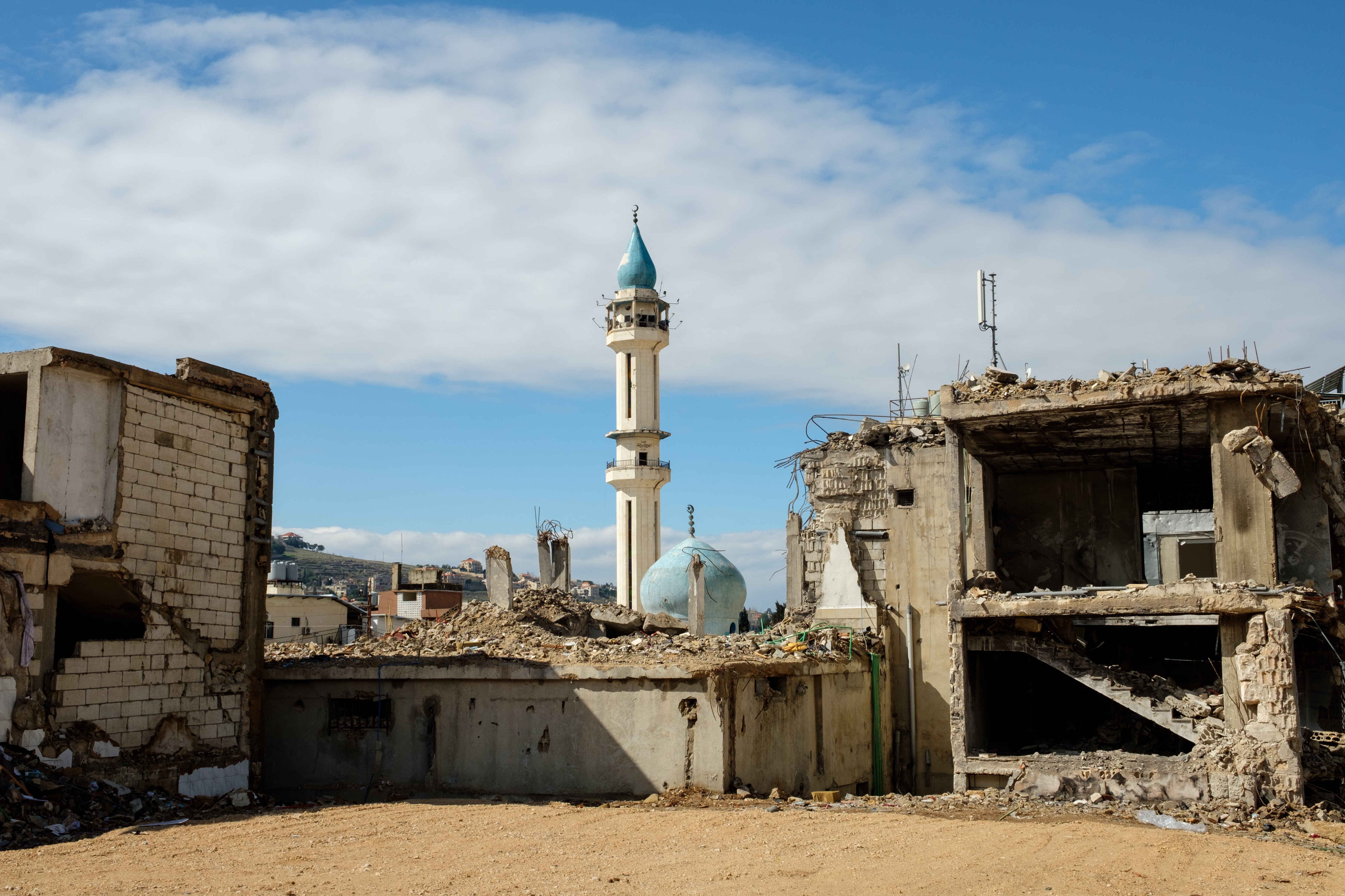 A minaret stands above a damaged mosque