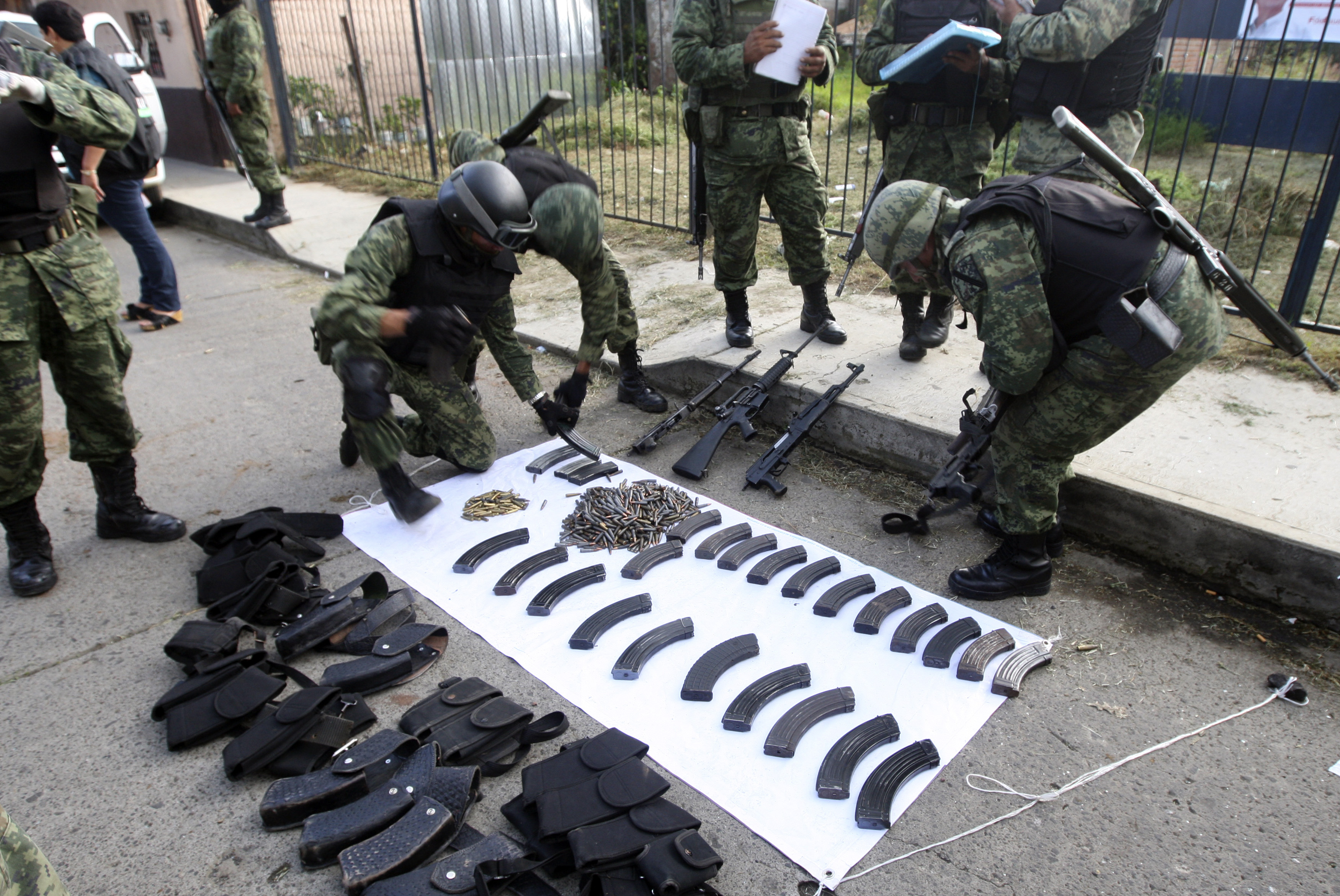 Soldiers look at confiscated weapons after a shootout with gunmen in downtown Tancitaro in the state of Michoacan October 19, 2011. Three gunmen, suspected members of the Caballeros Templarios, a new spin-off cartel in Michoacan state linked to the Gulf Cartel, and one soldier were killed in the shootout between the military and the gunmen, according to local media. REUTERS/Leovigildo Gonzalez (MEXICO - Tags: CRIME LAW CIVIL UNREST MILITARY)
