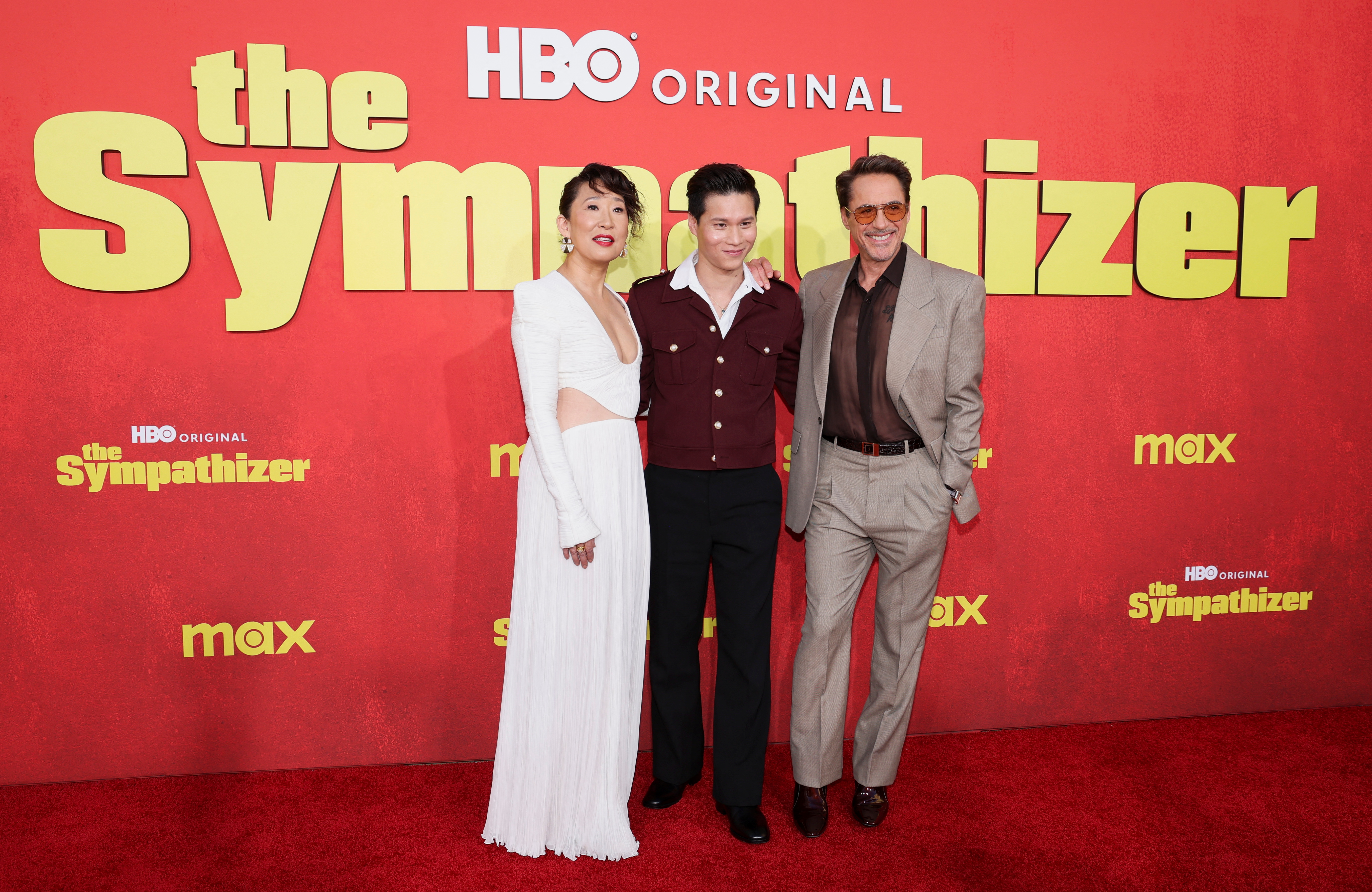 Robert Downey Jr., Sandra Oh and Hoa Xuande stand on the red carpet in front of a banner for the TV show "The Sympathizer"