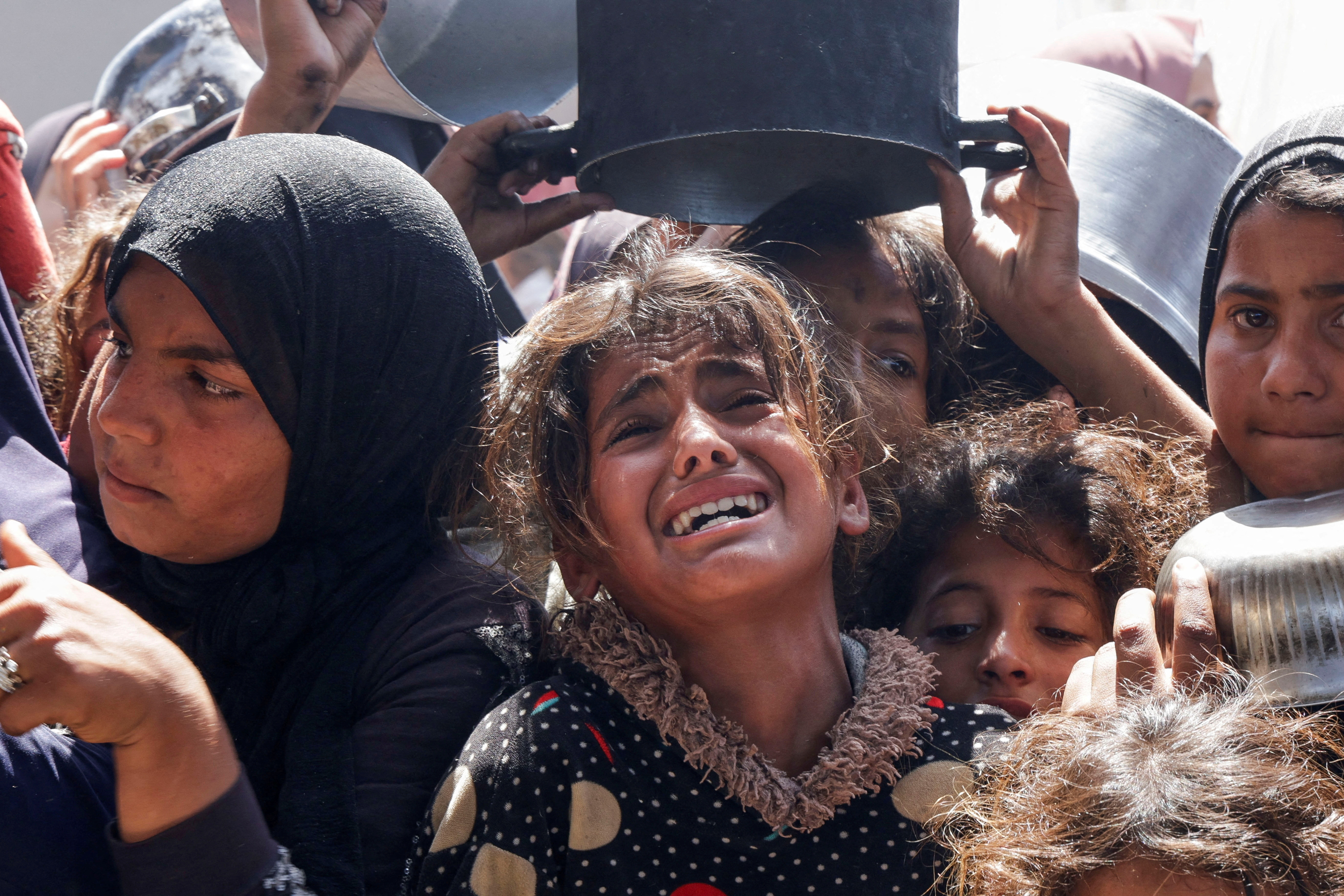 Palestinian children react as they gather to receive food at a charity kitchen in Gaza