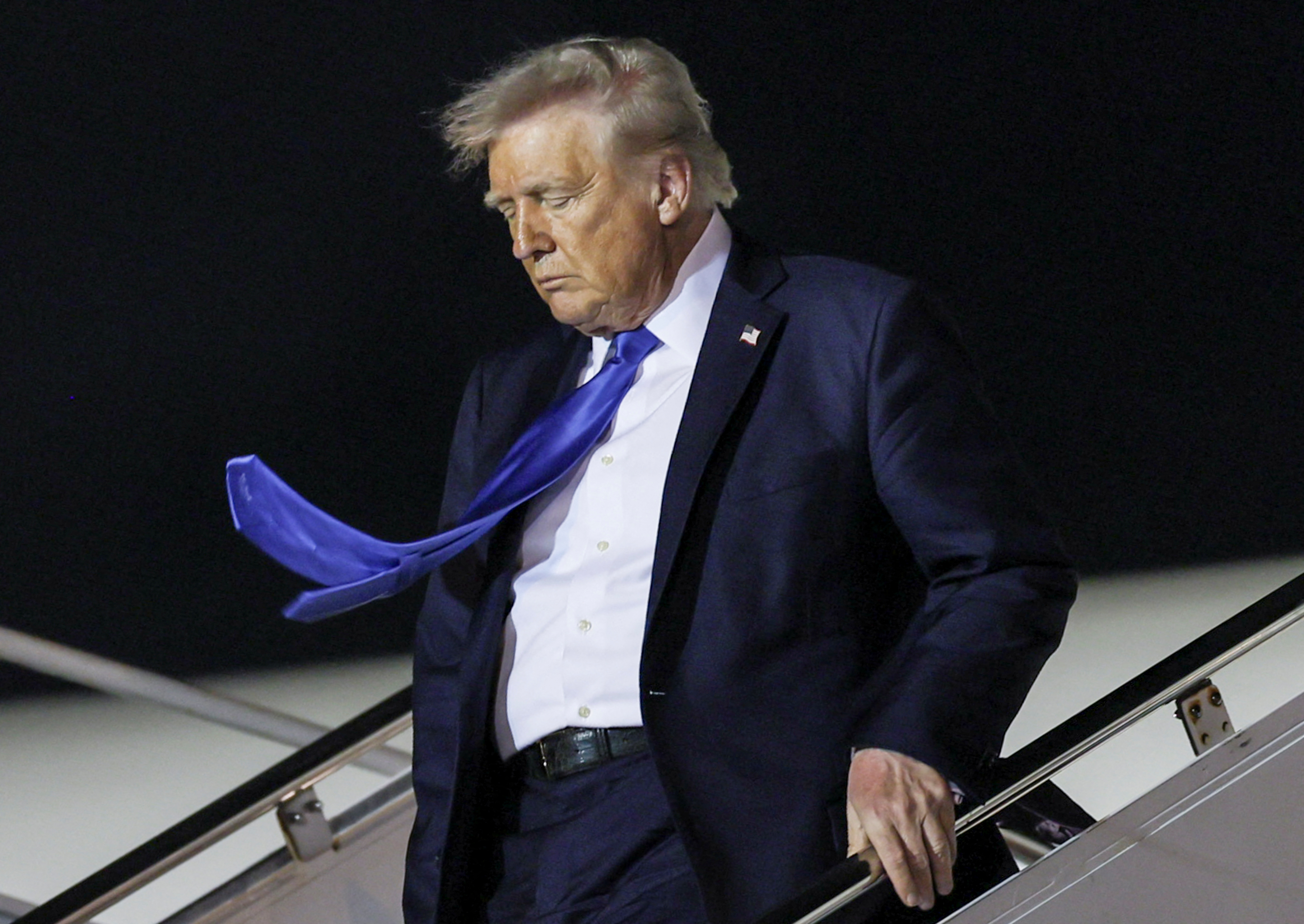 Donald Trump descends the stairs of Air Force One at night in Palm Beach.