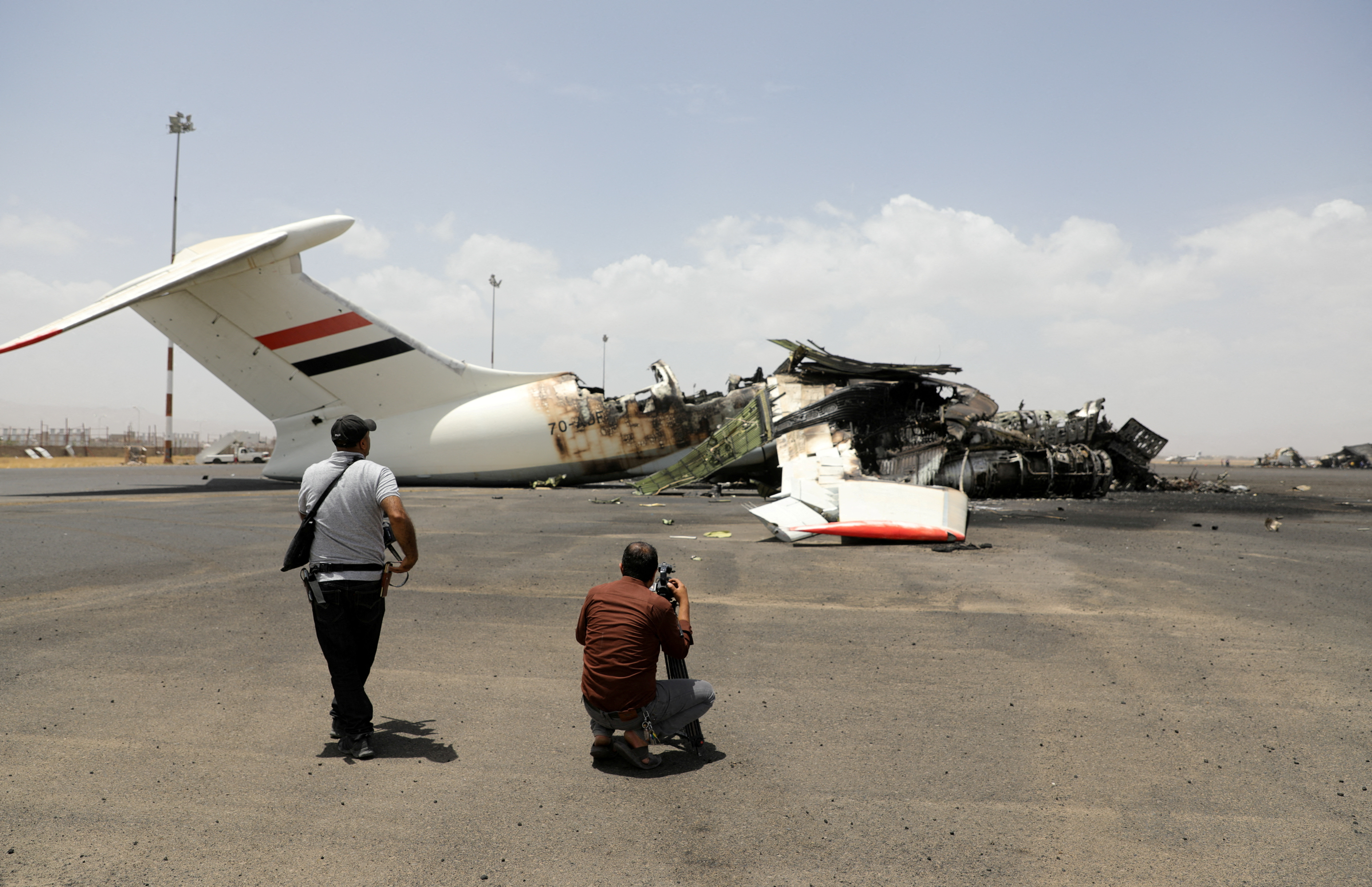 Members of the media take pictures of a destroyed plane at Sanaa International Airport, in the aftermath of an Israeli airstrike, in Sanaa,
