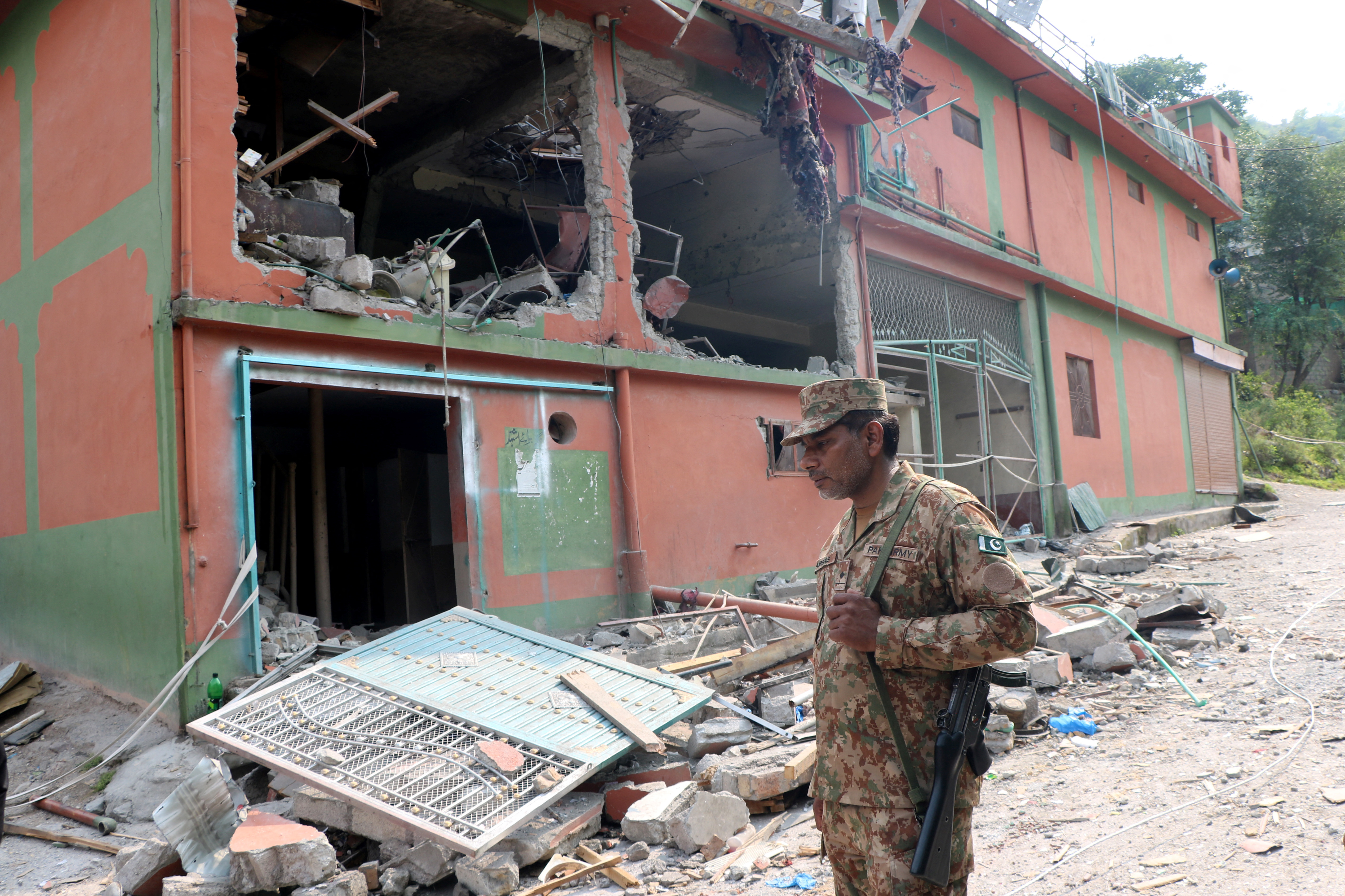 A Pakistan Army soldier stands in front of damaged Bilal Mosque