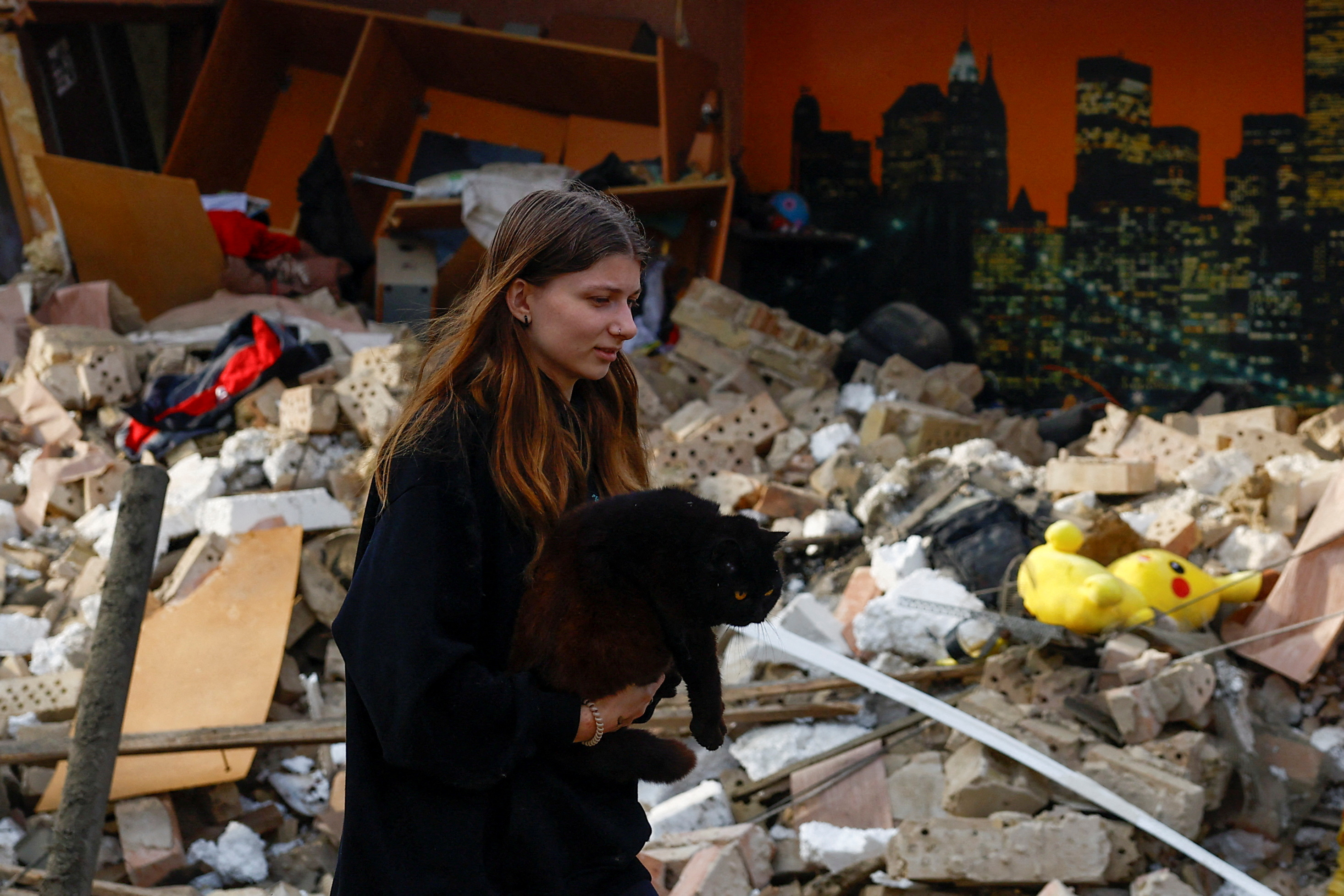 A resident carries a cat at the site of a house heavily damaged by a Russian drone strike outside Kyiv