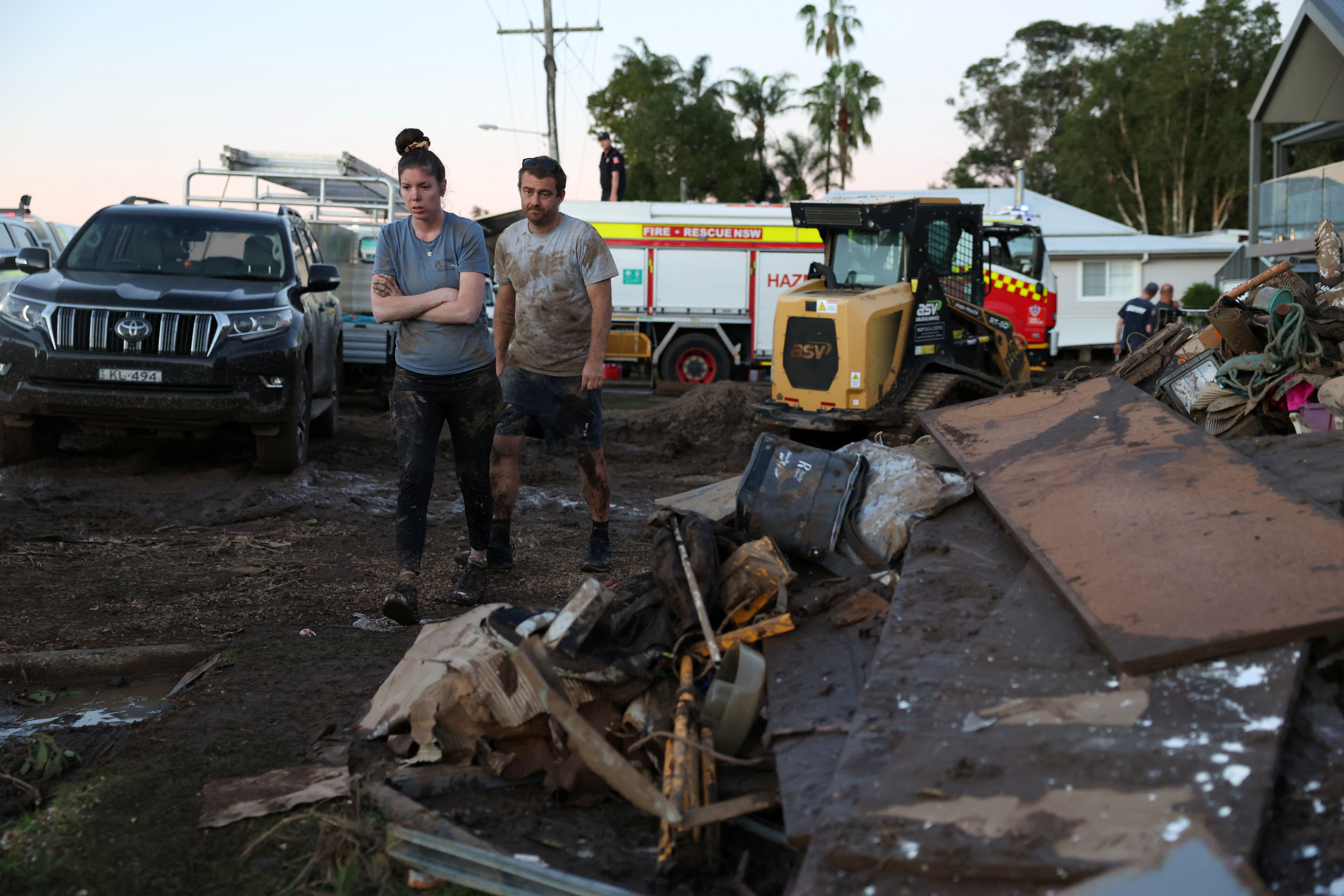 Volunteers walk past debris outside residential properties after floods in Australia