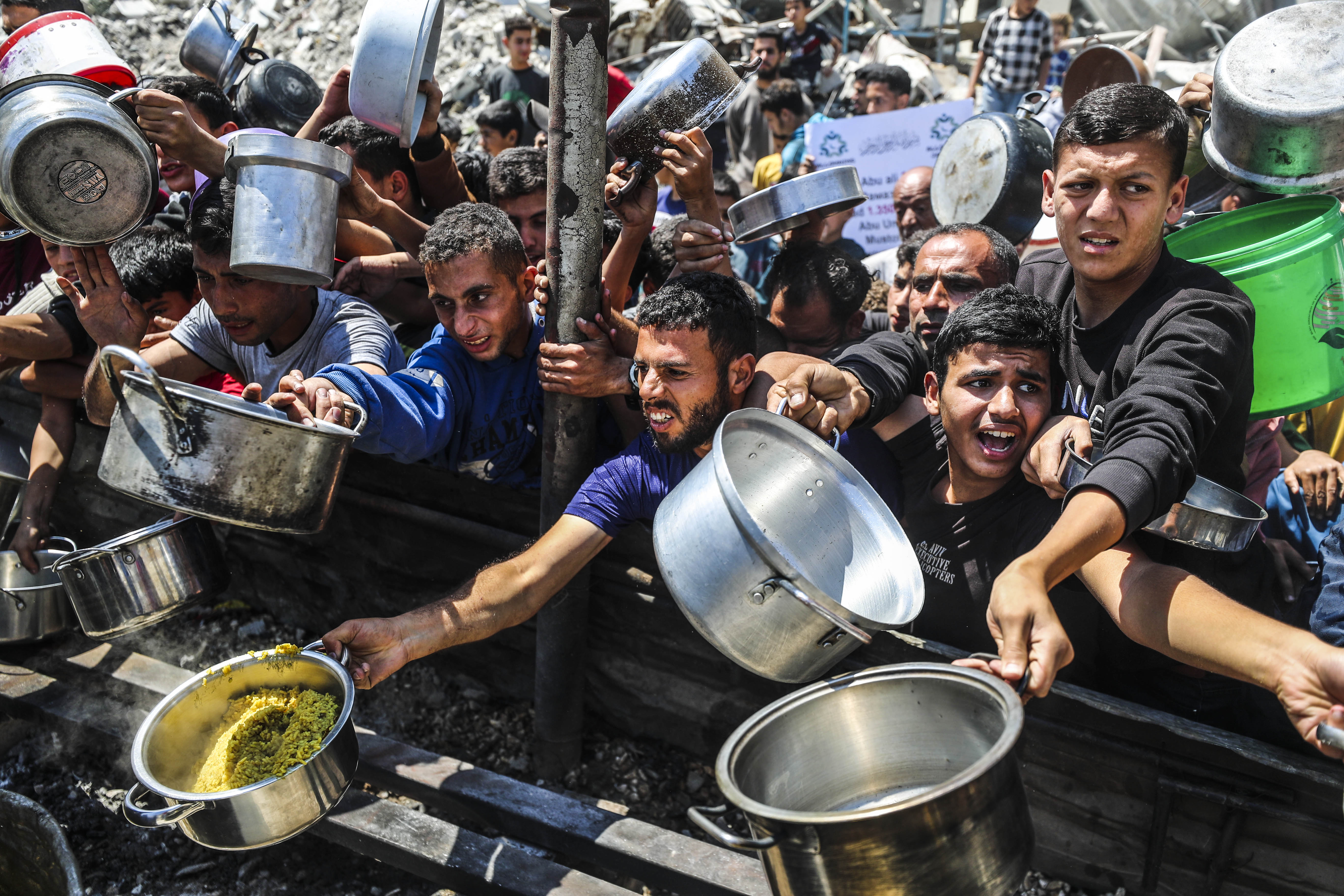 Displaced Palestinians queue for hot meals.