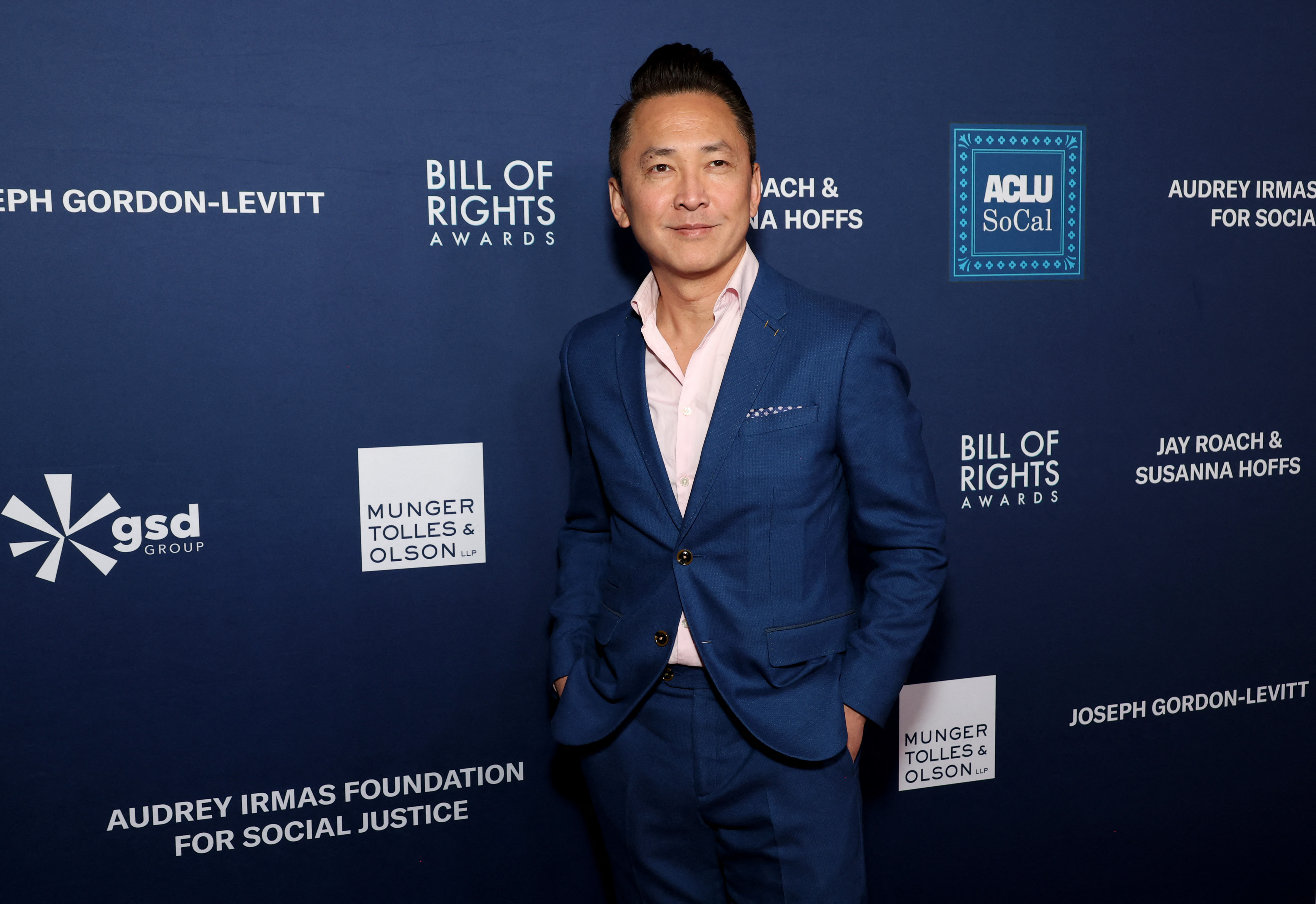 Viet Thanh Nguyen, wearing a blue suit, walks on a red carpet for the Bill of Rights Awards.