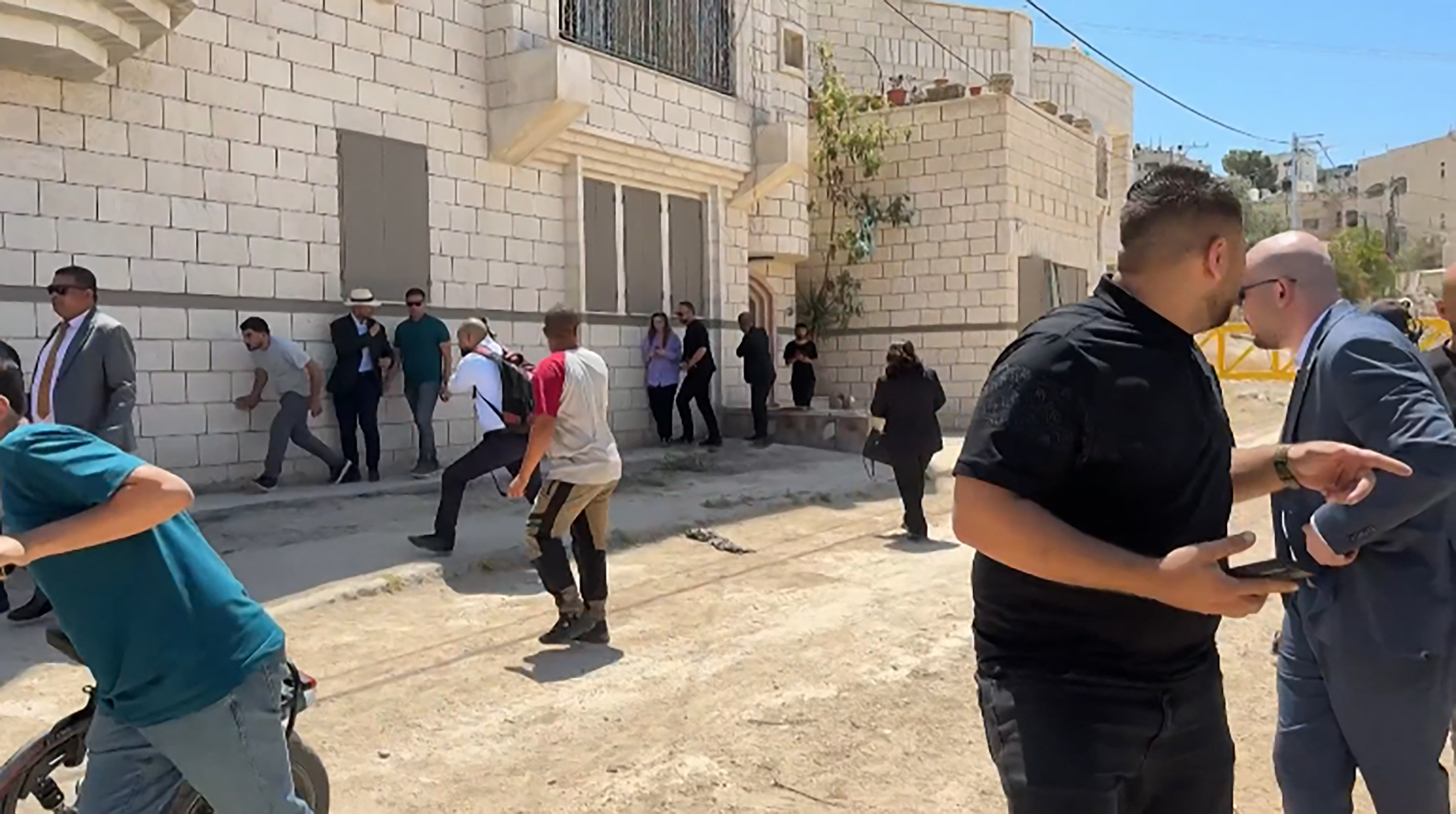 This frame grab from AFPTV footage shows members of a diplomatic delegation reacting after shots were fired as they gathered in the eastern entrance of Jenin camp during a visit to the city of Jenin, on May 21, 2025, amid an ongoing Israeli military offensive in the occupied West Bank. [Mohammad Ateeq / AFPTV / AFP]
