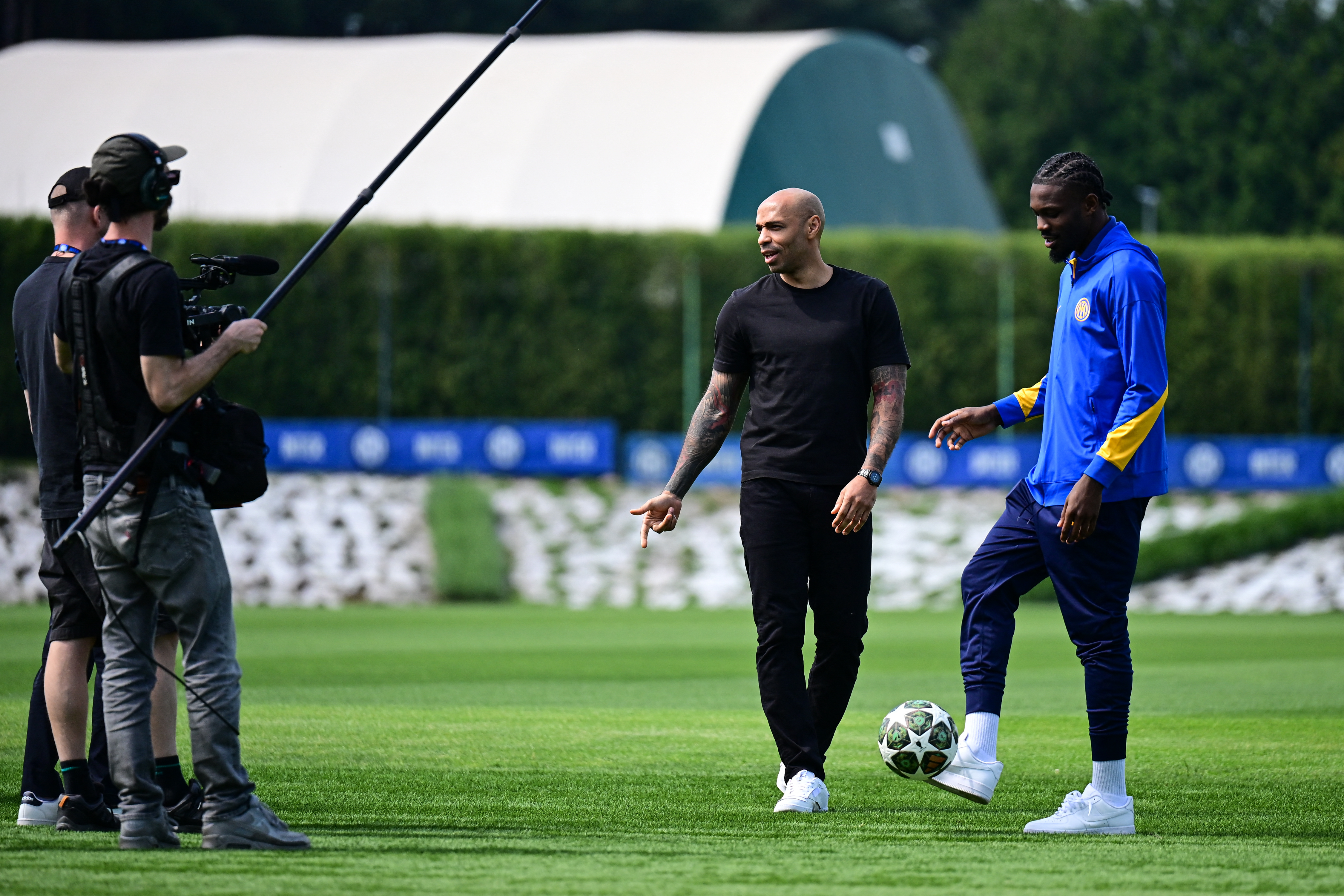 Former football player Thierry Henry stands reacts next to Inter Milan's French forward Marcus Thuram