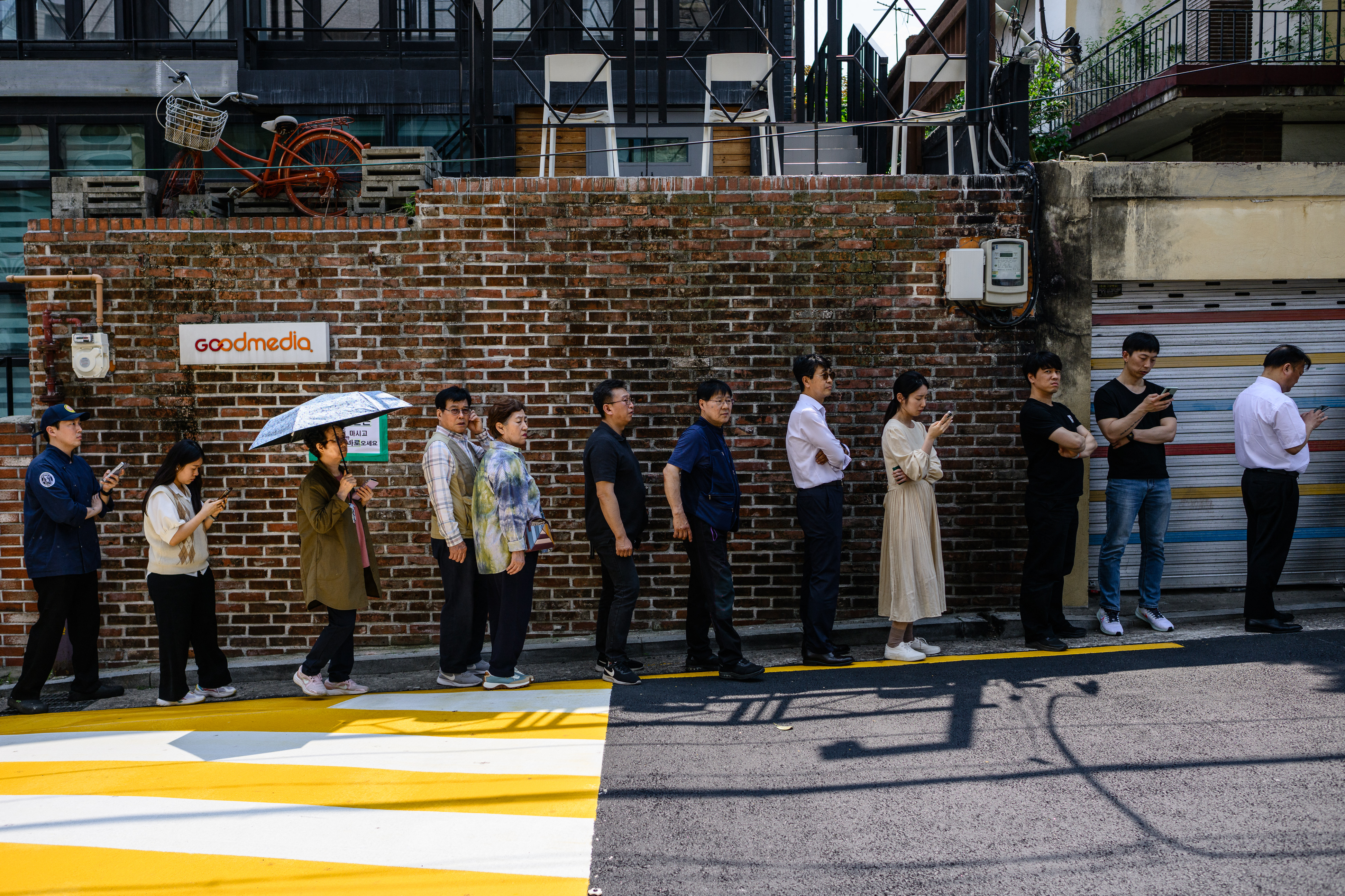 People queue up on a street near a polling station to cast early votes for the upcoming presidential election in Seoul on May 29, 2025. (Photo by ANTHONY WALLACE / AFP)