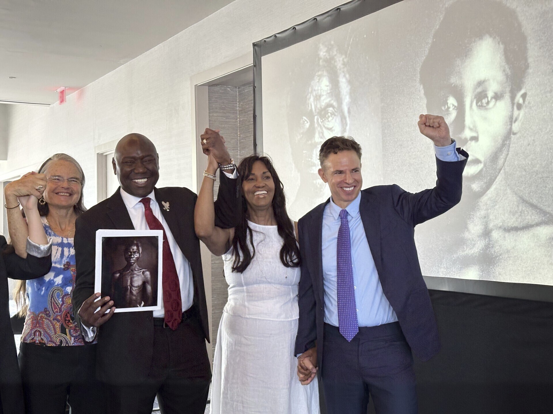 Susanna Moore, Tamara Lanier, Ben Crump and Josh Koskoff celebrate in front of the portraits of Renty and Delia