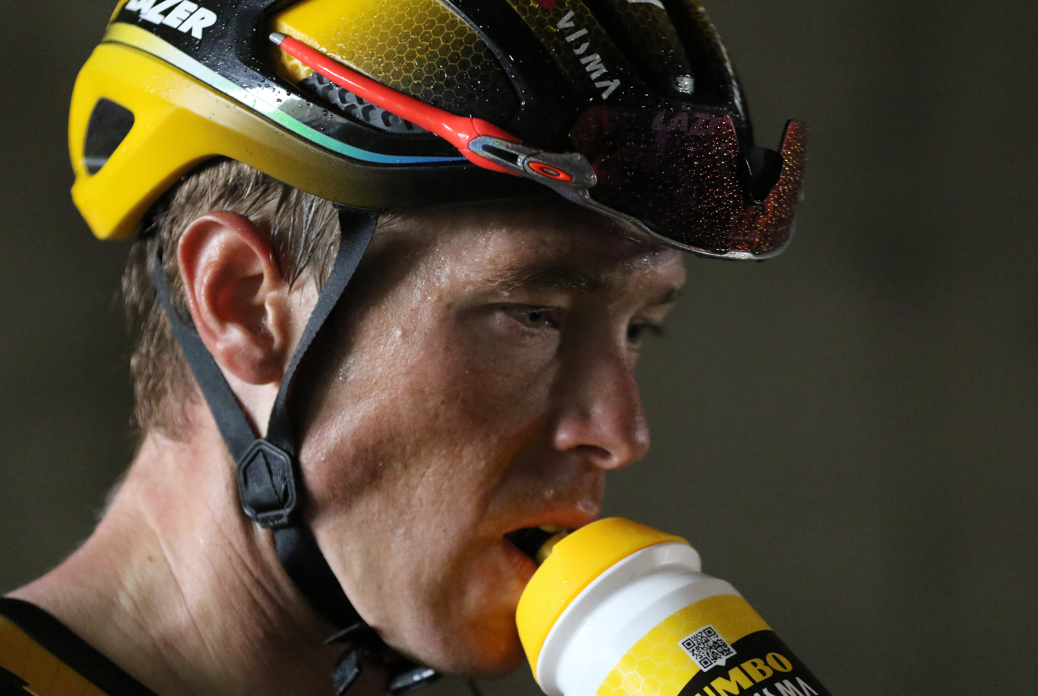 Rohan Dennis drinks from a flask as he wears a helmet.