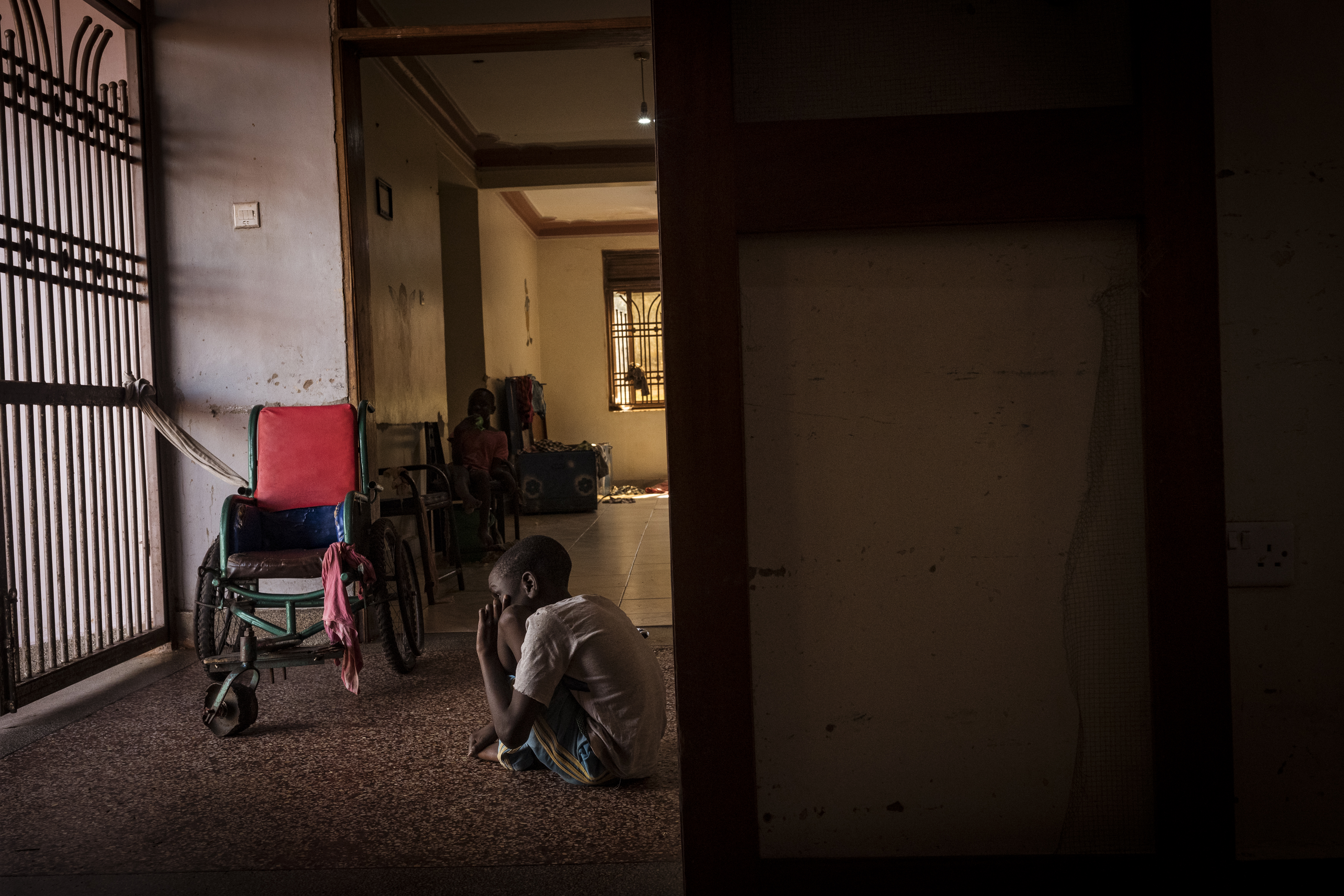 Bugembe, Jinja District, Uganda. Joseph, 10, sits alone outside the therapy room at the Home of Hope. [Christopher Hopkins/Al Jazeera]