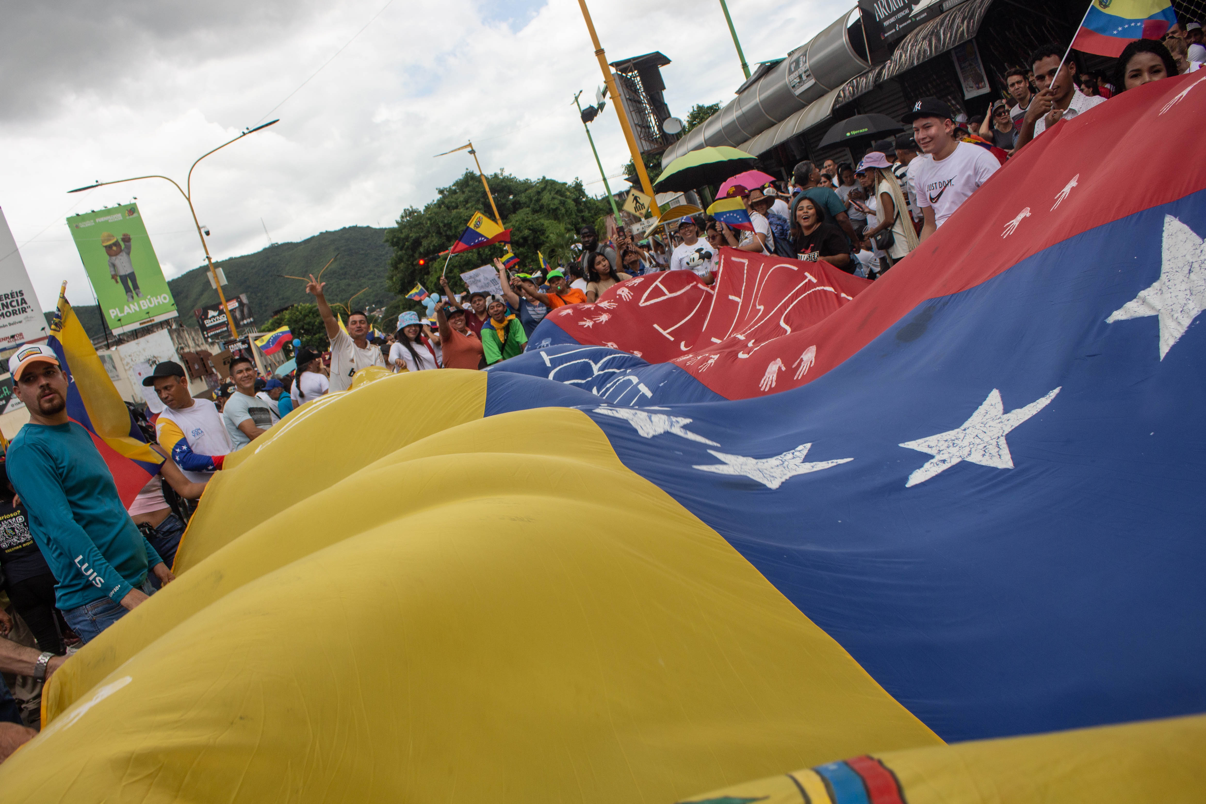 Opposition members rally around a giant Venezuelan flag.