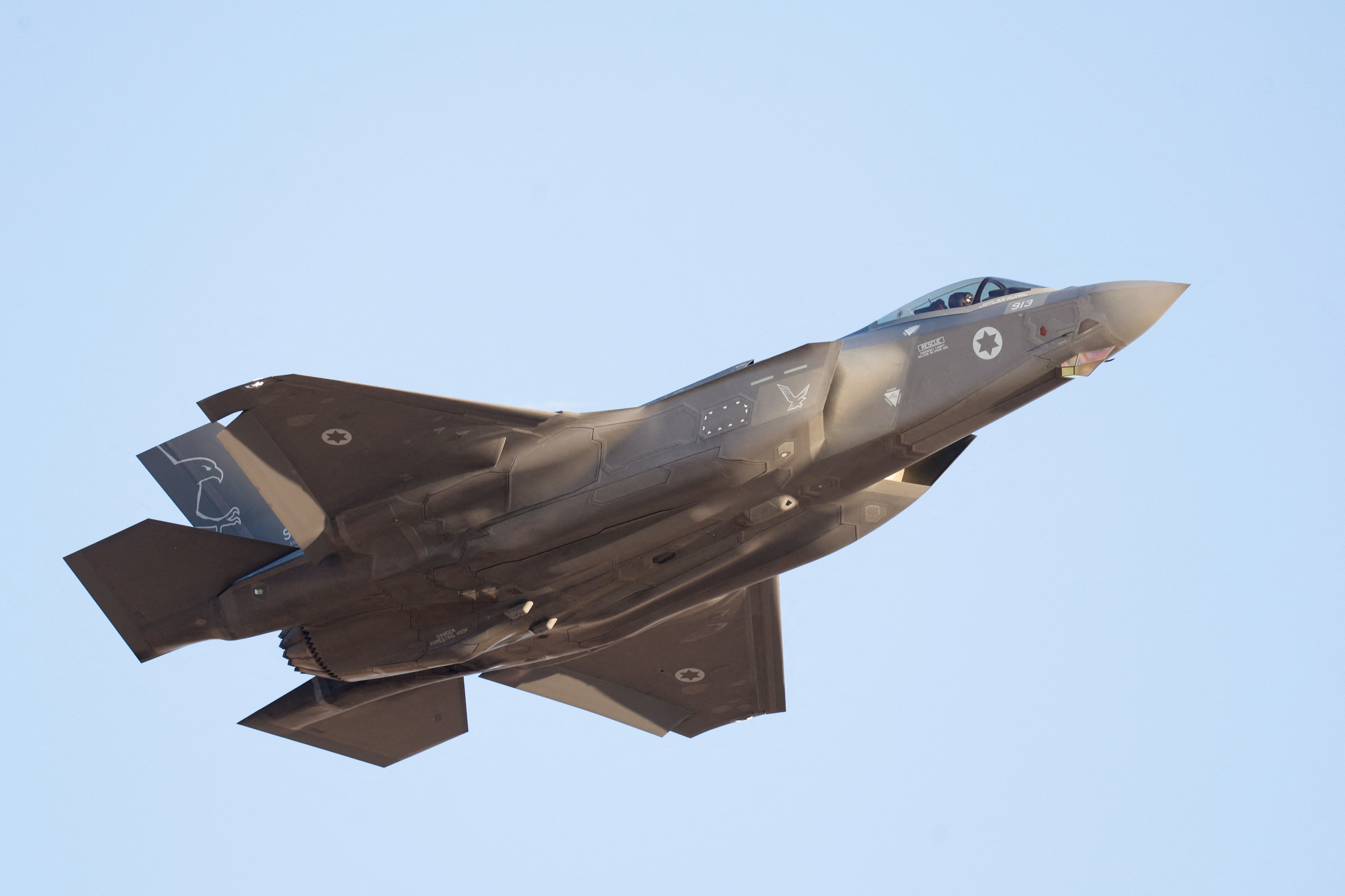 An Israeli F-35 fighter jet flying in a blue sky.