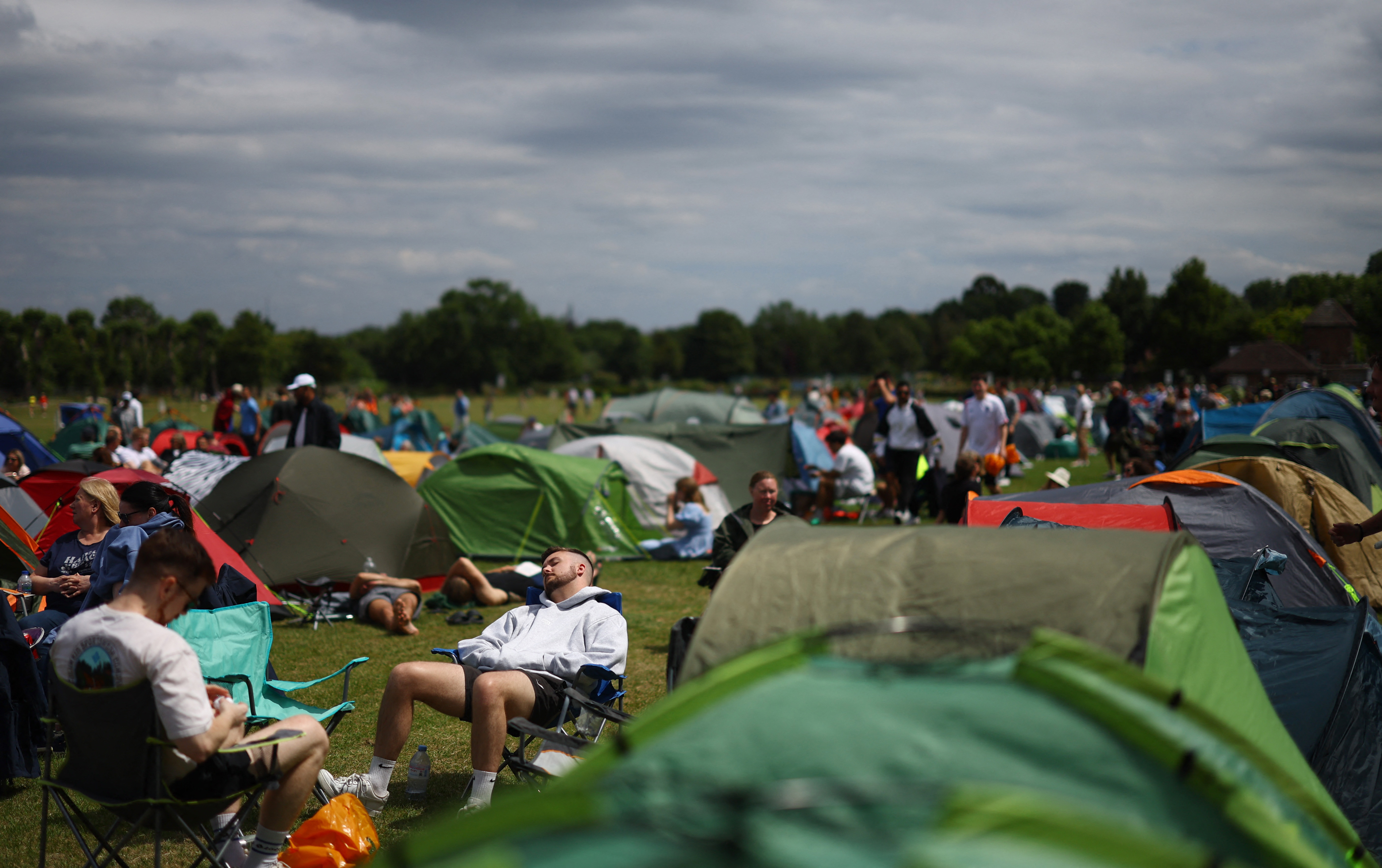 Tennis - Wimbledon - All England Lawn Tennis and Croquet Club, London, Britain - June 30, 2024 People relax as they queue in tents at a public park opposite the grounds of Wimbledon ahead of the competition REUTERS/Hannah Mckay