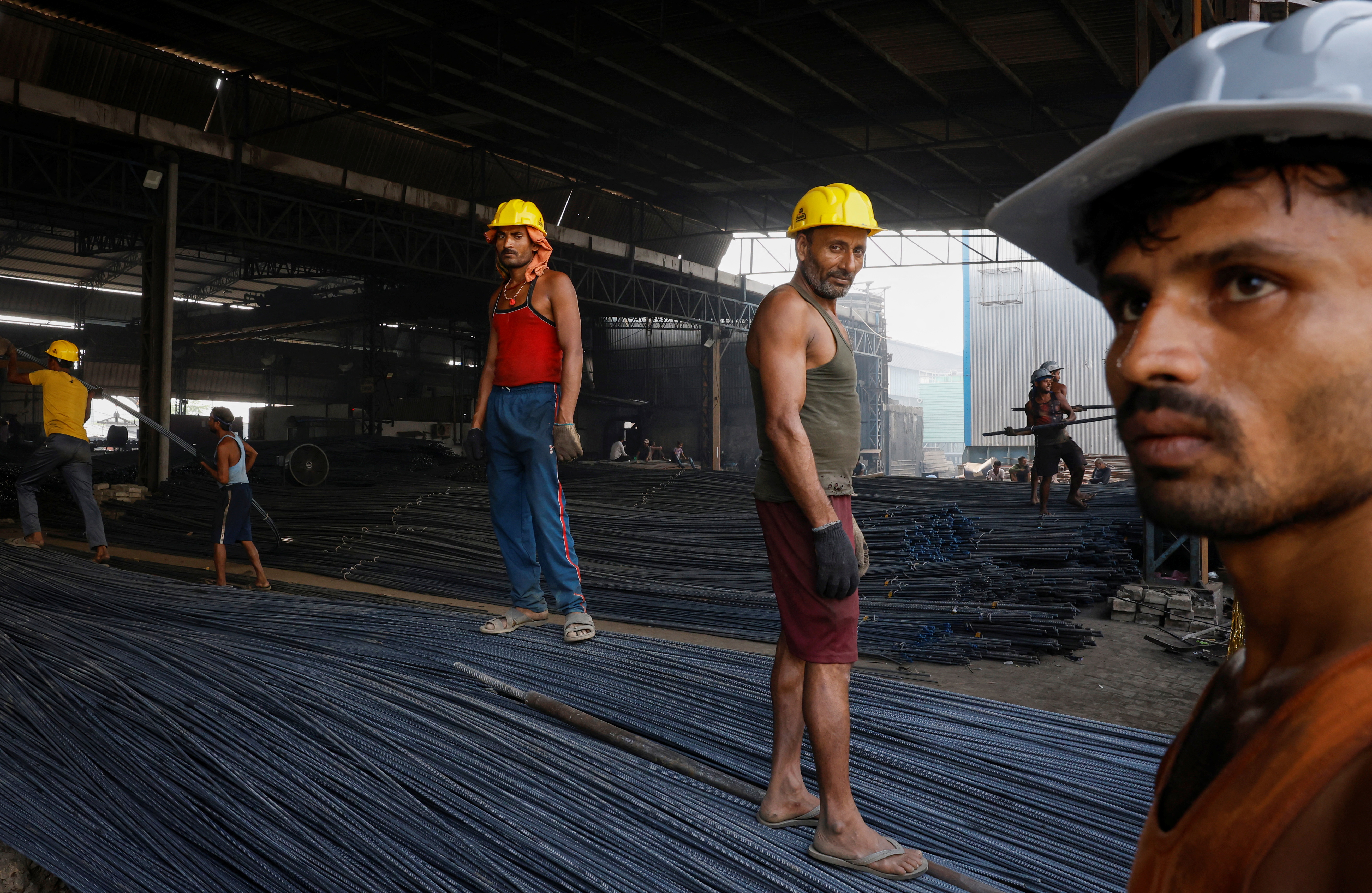 Workers stand on TMT bars at a factory in Mandi Gobindgarh, in the northern state of Punjab, India, October 19, 2024. REUTERS/Priyanshu Singh