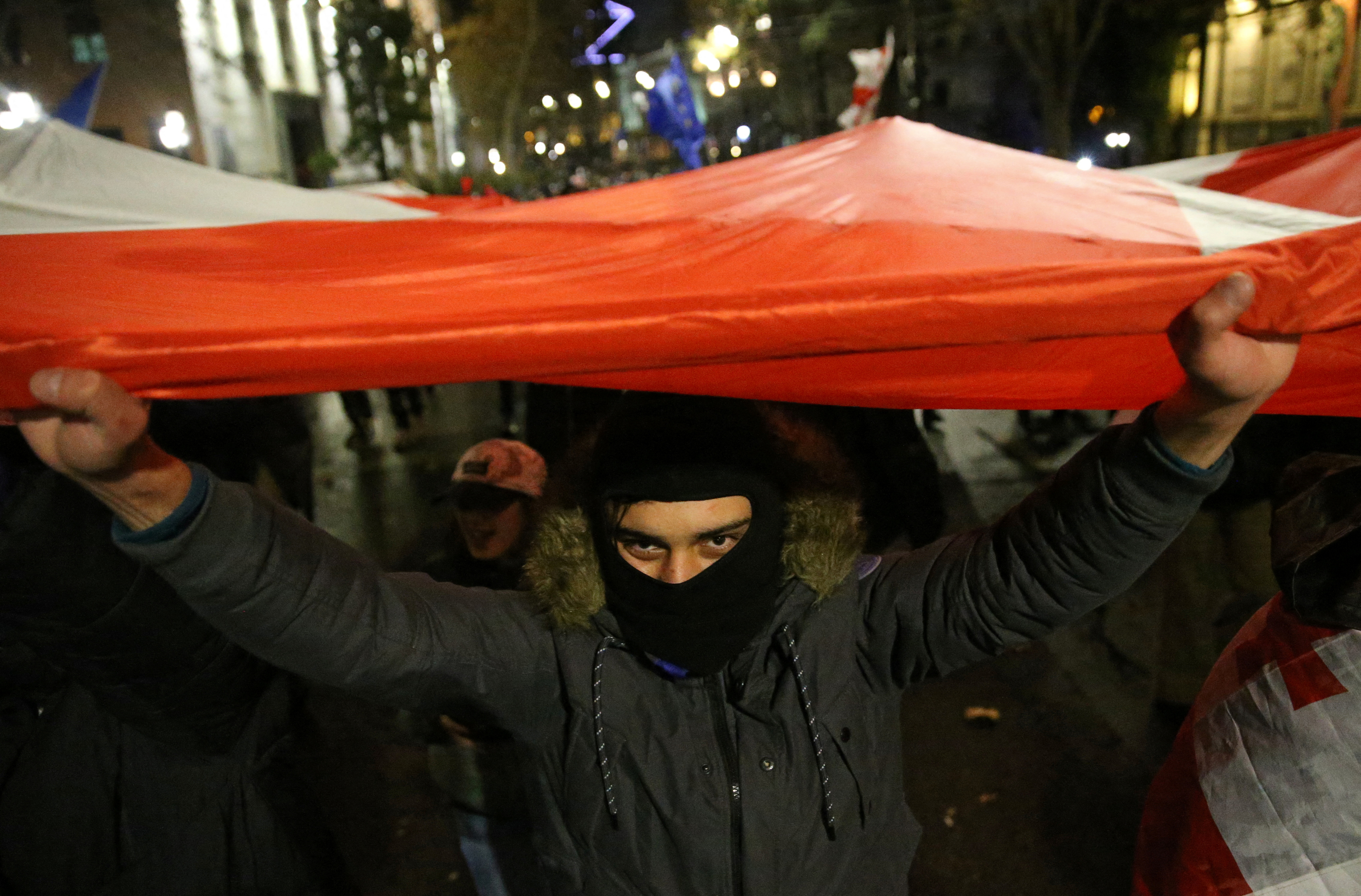 A demonstrator carries the Georgian flag during a rally held by supporters of Georgia's opposition