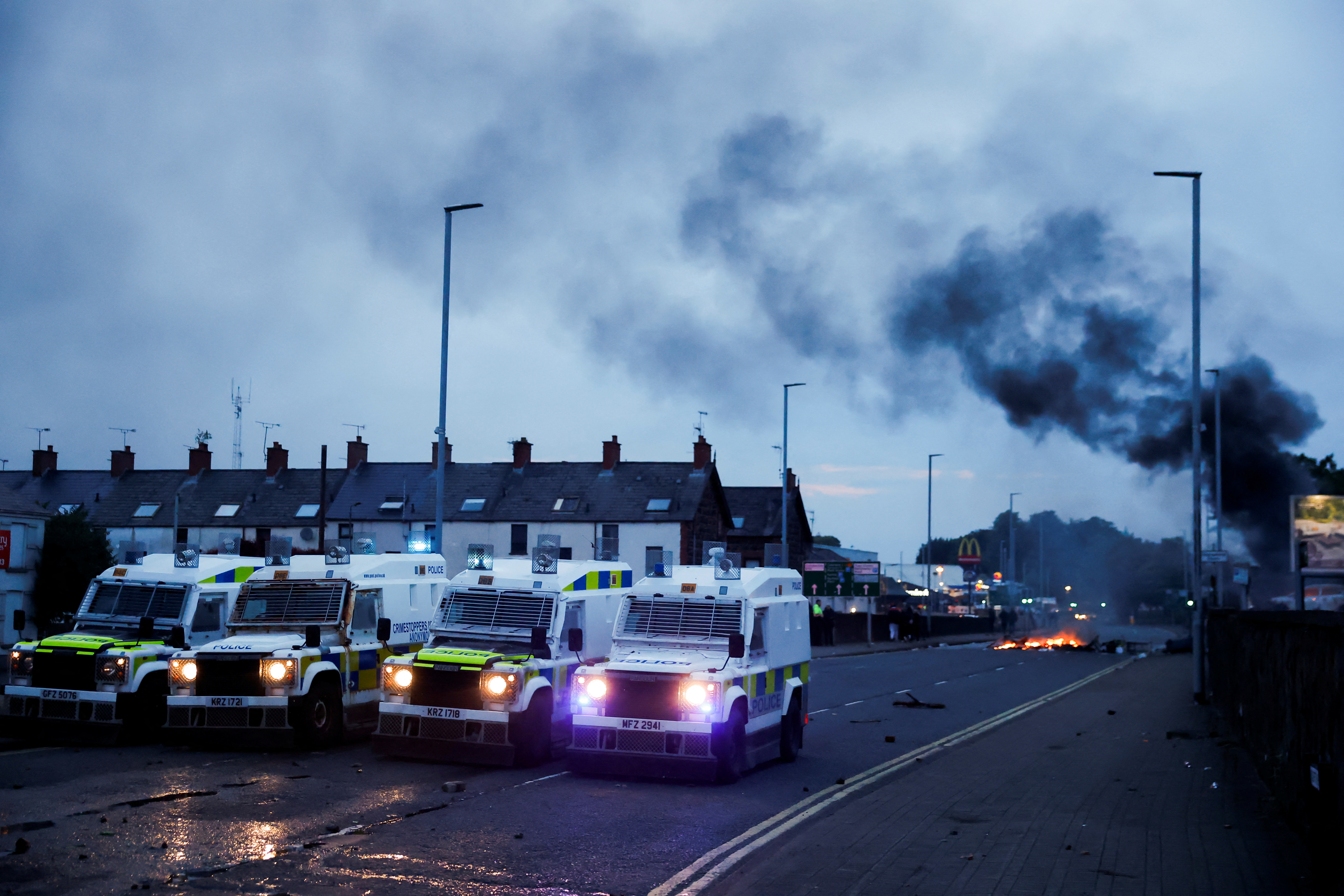 Official vehicles are parked as flames rise during a second night of riots, in Ballymena, Northern Ireland, June 10, 2025. REUTERS/Clodagh Kilcoyne