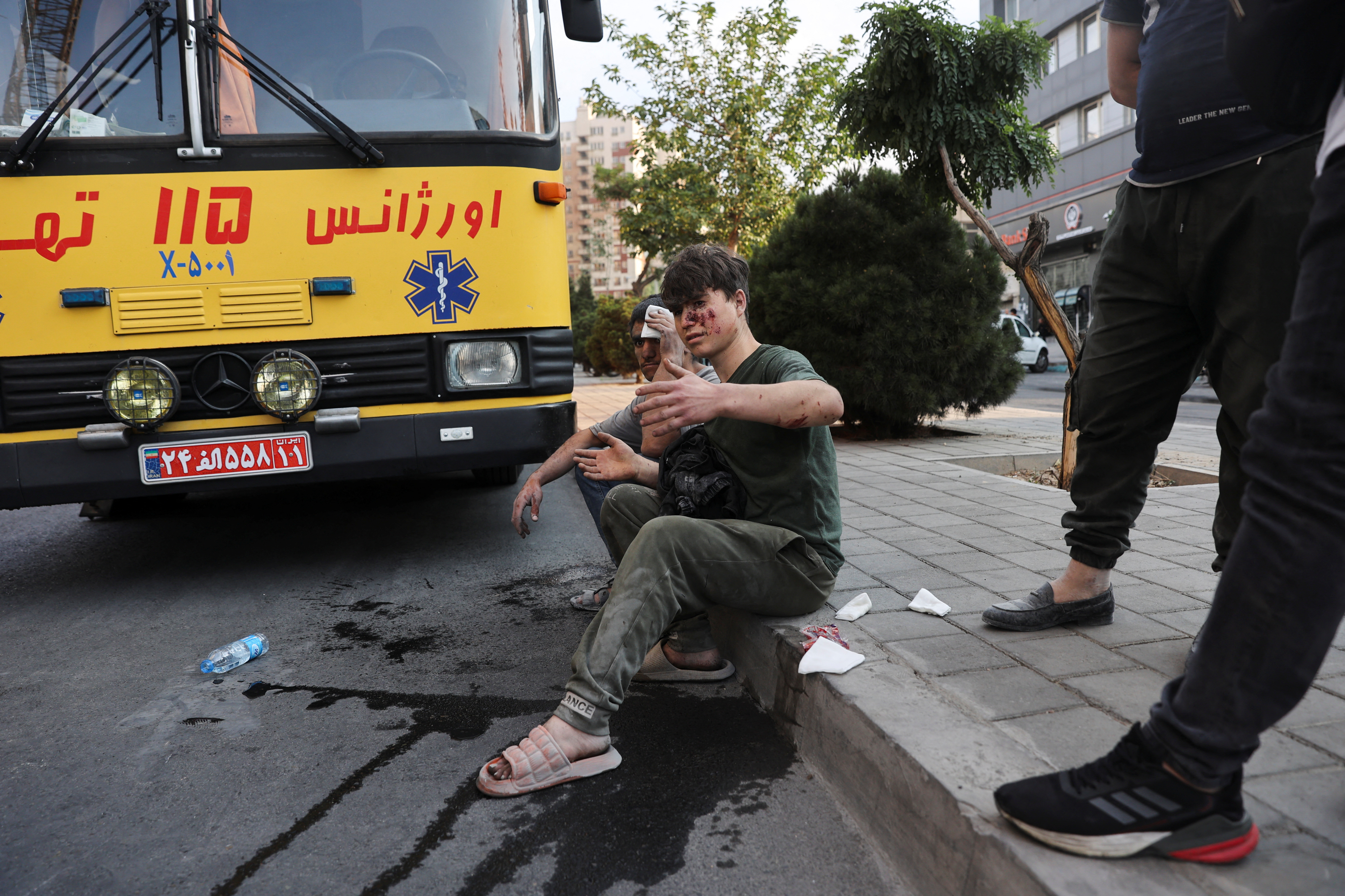 An injured person sits on a roadside in the aftermath of Israeli strikes, in Tehran, Iran, June 13, 2025. Majid Asgaripour/WANA (West Asia News Agency) via REUTERS ATTENTION EDITORS - THIS PICTURE WAS PROVIDED BY A THIRD PARTY TPX IMAGES OF THE DAY