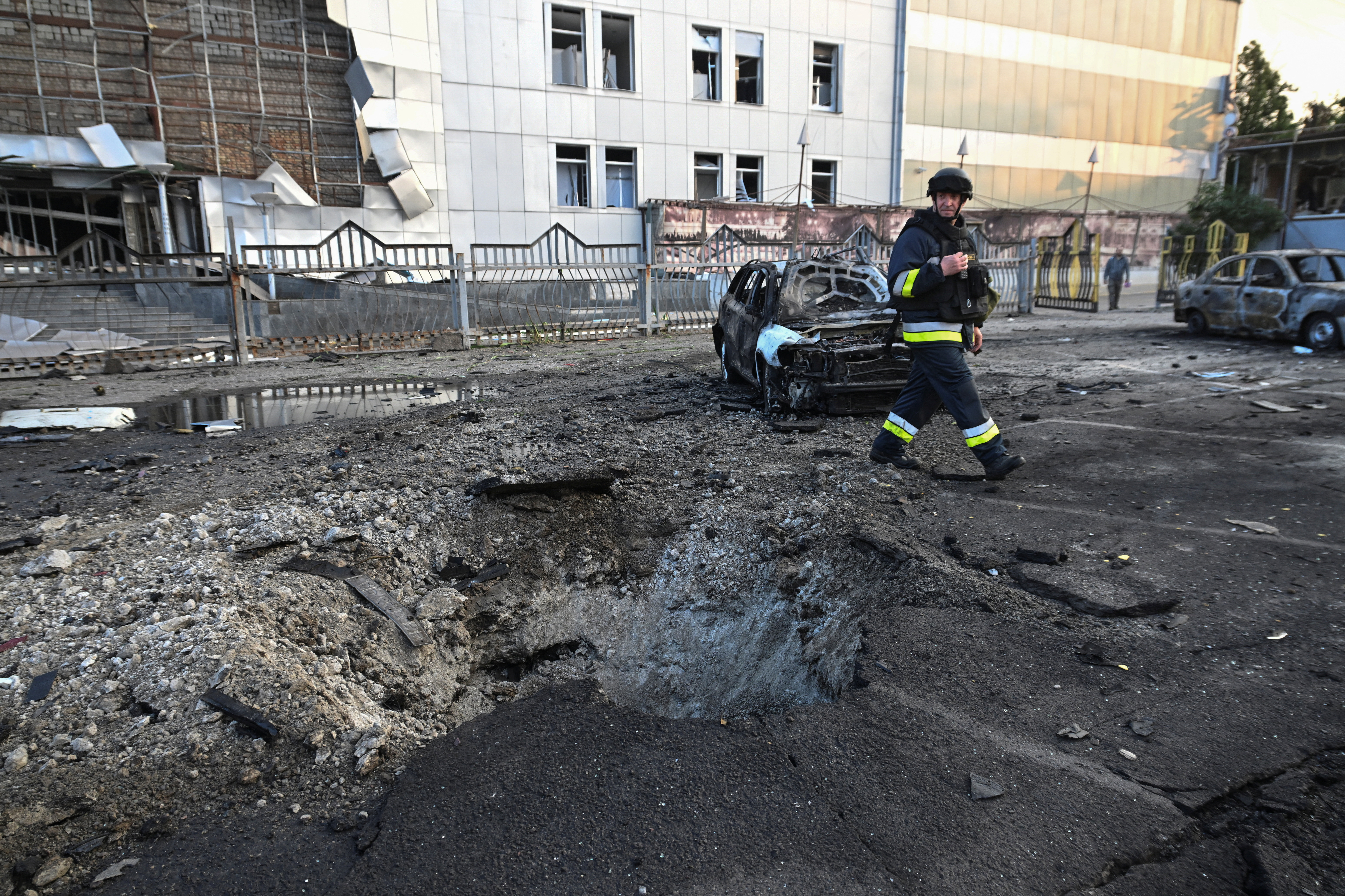 A rescuer walks next to destroyed cars and a building of shopping mall damaged by a Russian drone strike, amid Russia's attack on Ukraine