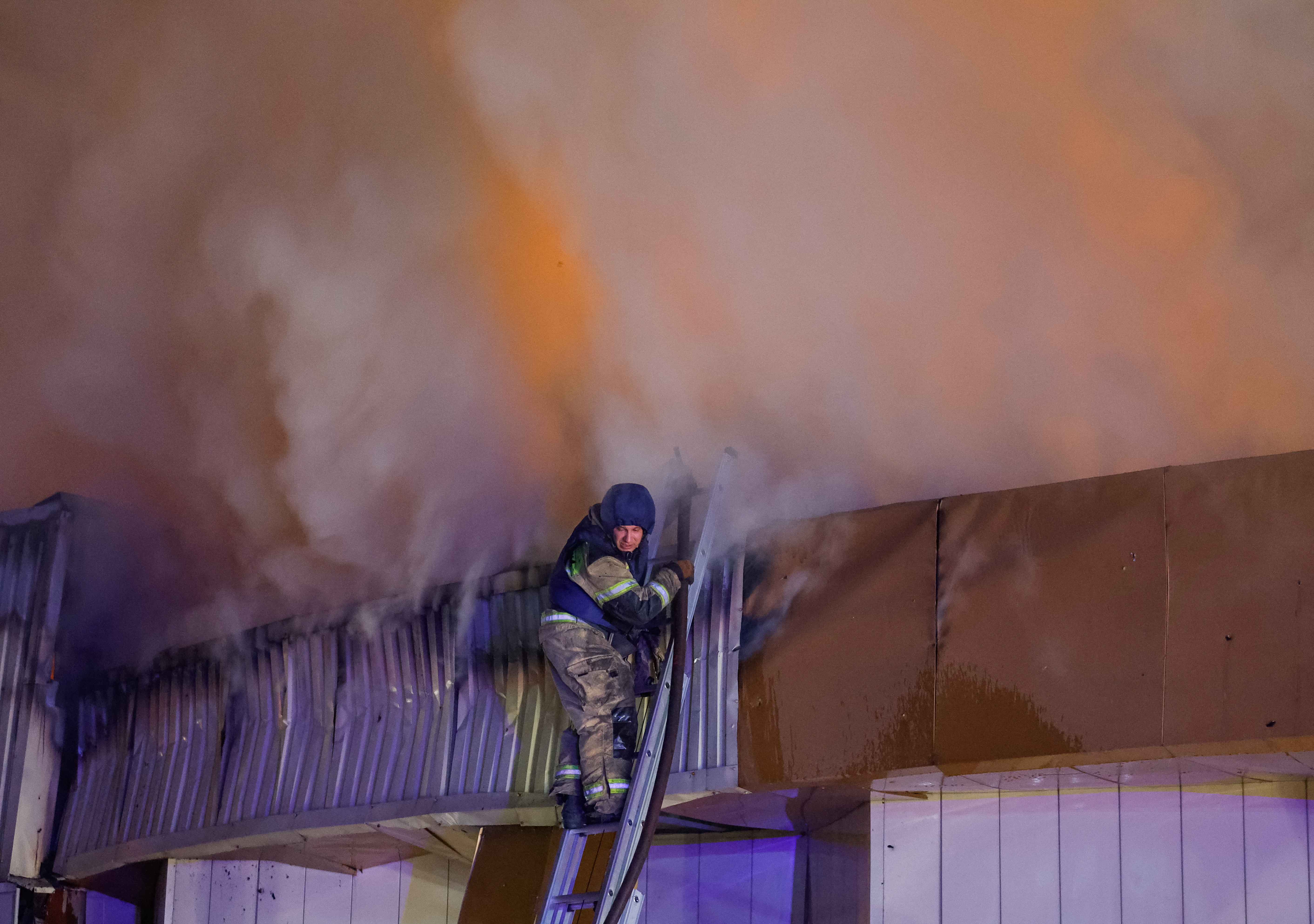 a firefighter sprays water on an orange fire
