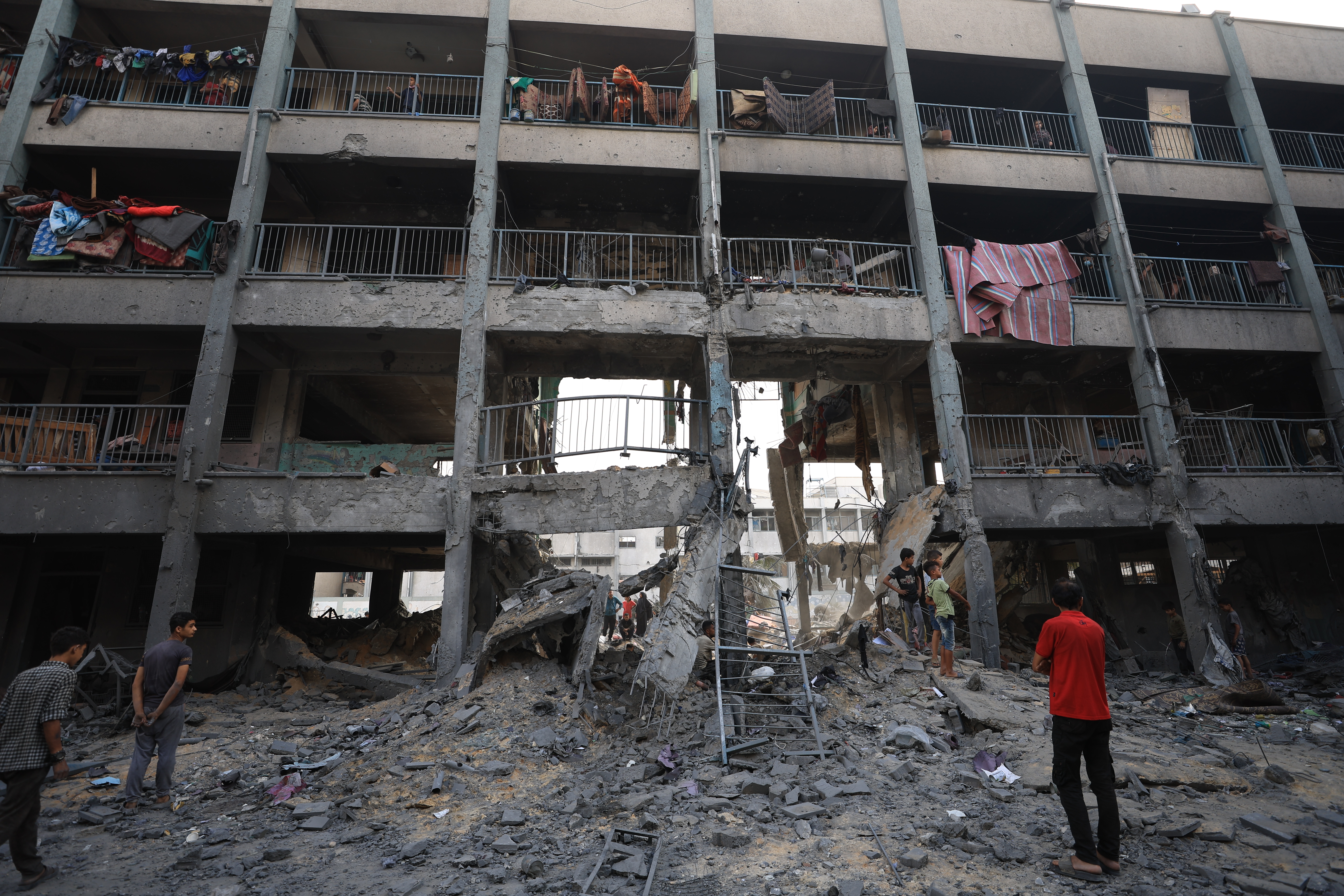 Palestinians inspect the destruction of buildings after Israeli attacks on a school.