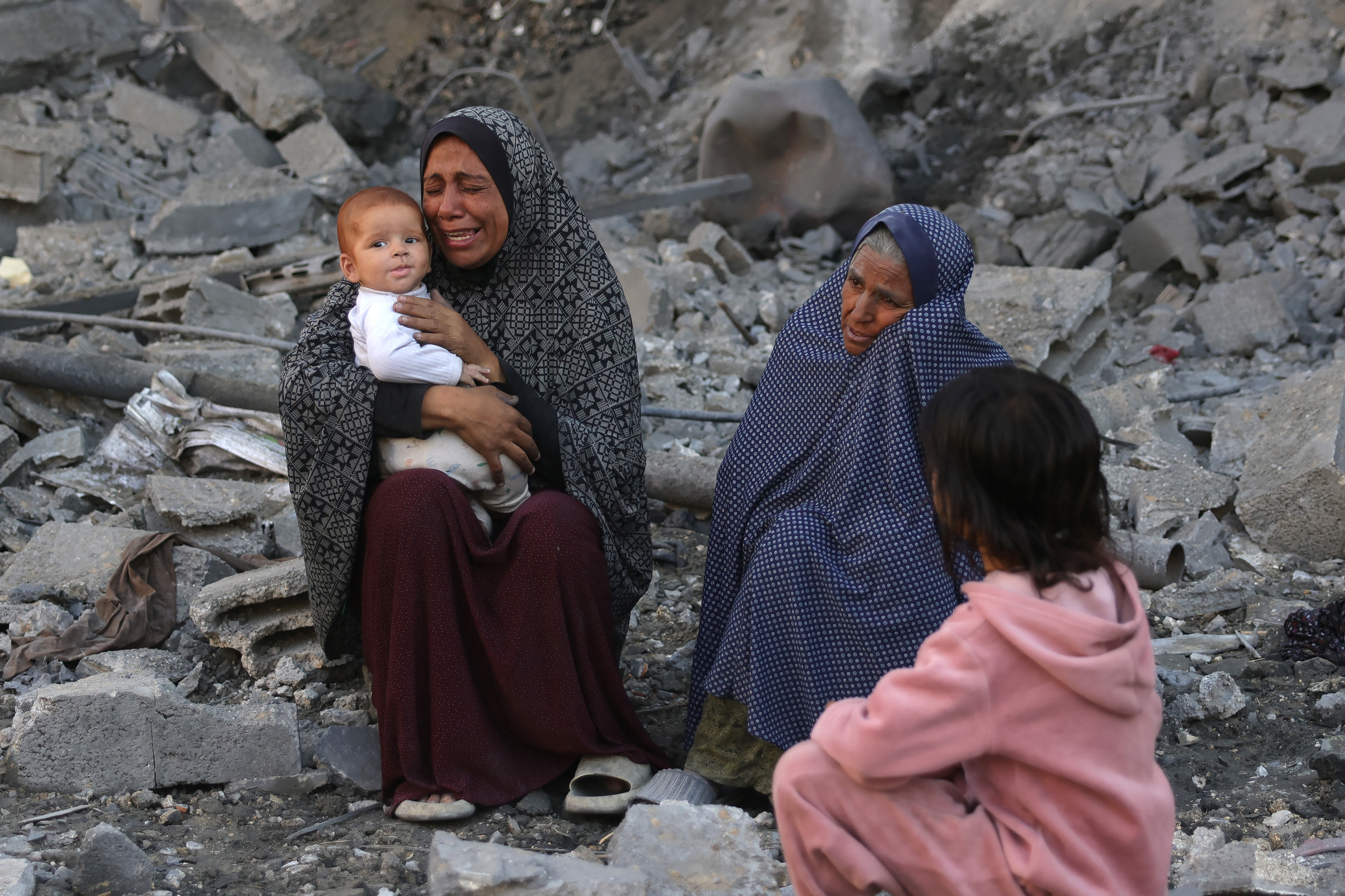 A woman holding a baby cries as Palestinians check the site of an overnight Israeli strike, in Jabalia in the central Gaza Strip, on May 30, 2025, amid the war between Israel and the Palestinian Hamas militant movement. Israel's far-right National Security Minister Itamar Ben Gvir said on May 30 it was time to use "full force" in Gaza, after Hamas said a new US-backed truce proposal failed to meet its demands. (Photo by Bashar TALEB / AFP)