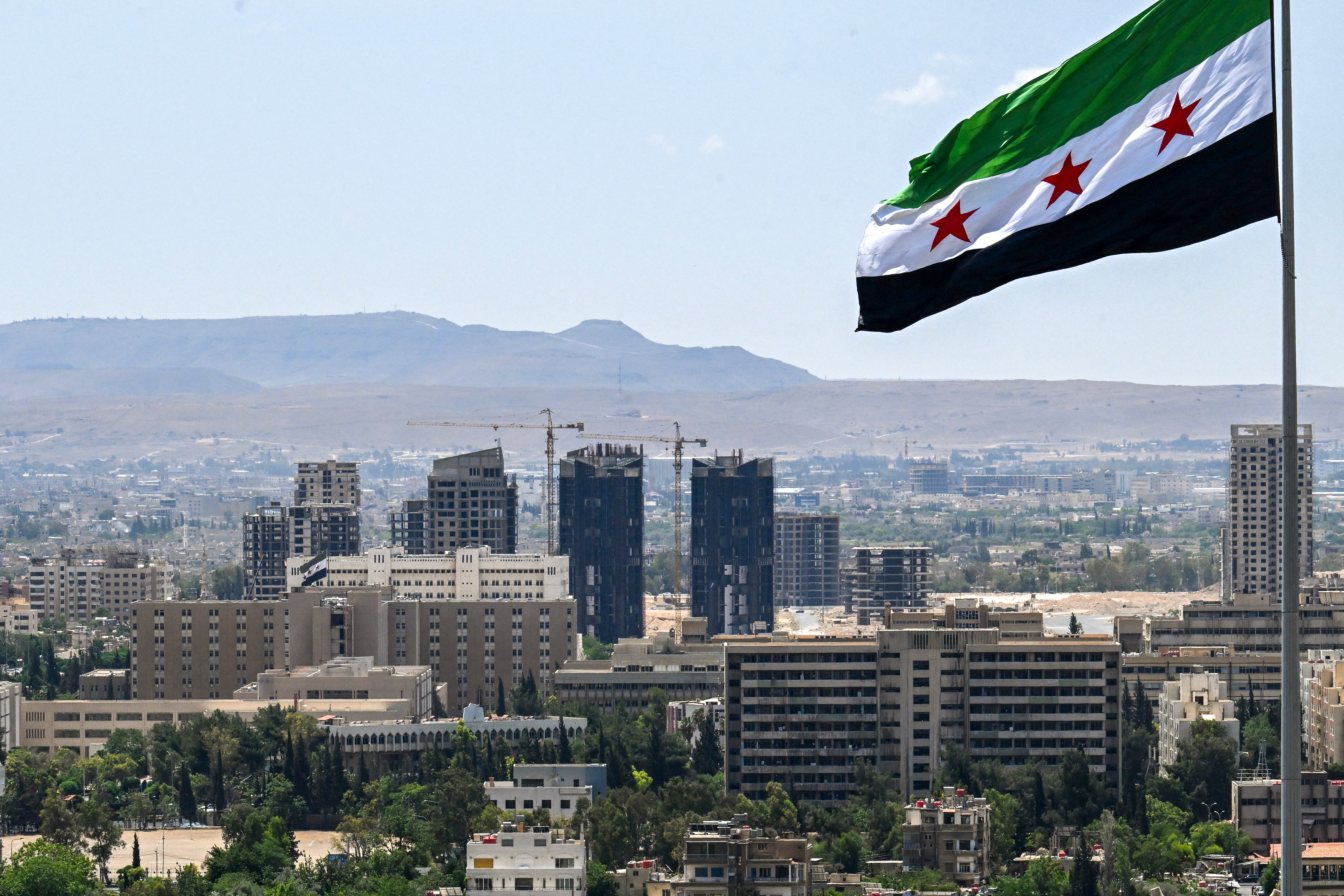 A large Syrian flag flutters above Tishreen Park in Damascus