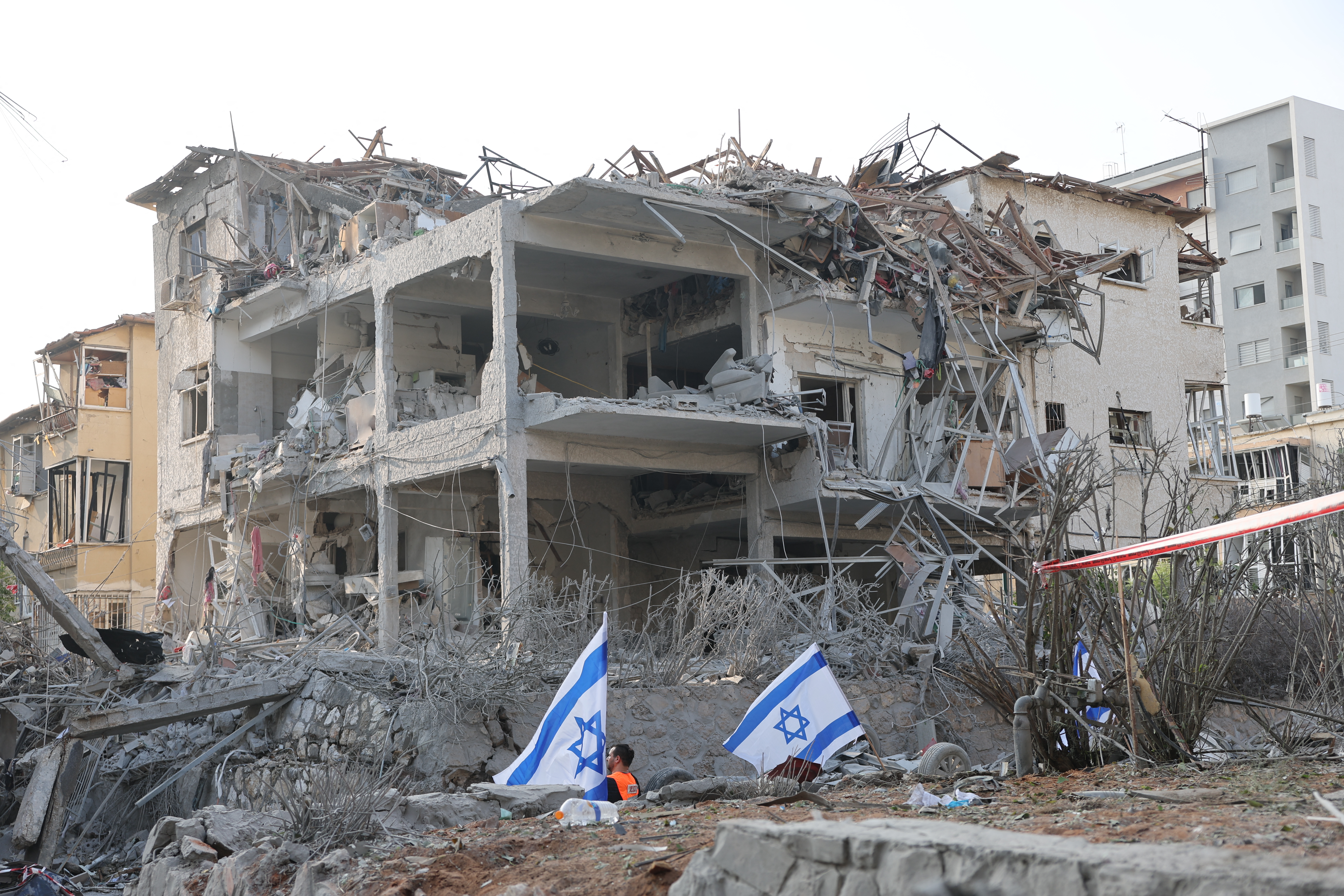 Israeli flags stand near damaged buildings in the Israeli city of Ramat Gan near Tel Aviv