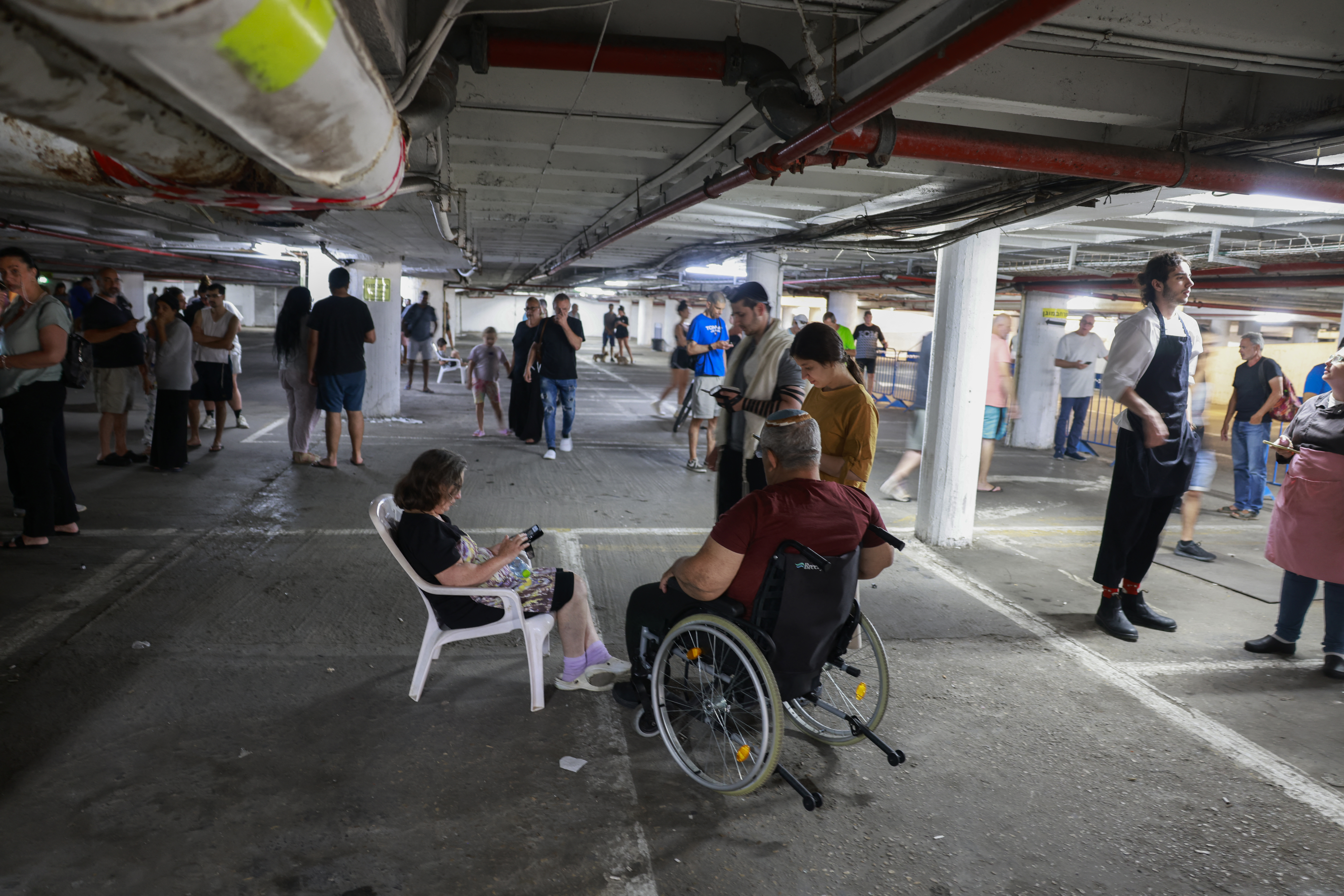 People take shelter in a parking lot in Tel Aviv amid a fresh barrage of Iranian rockets on June 17, 2025.