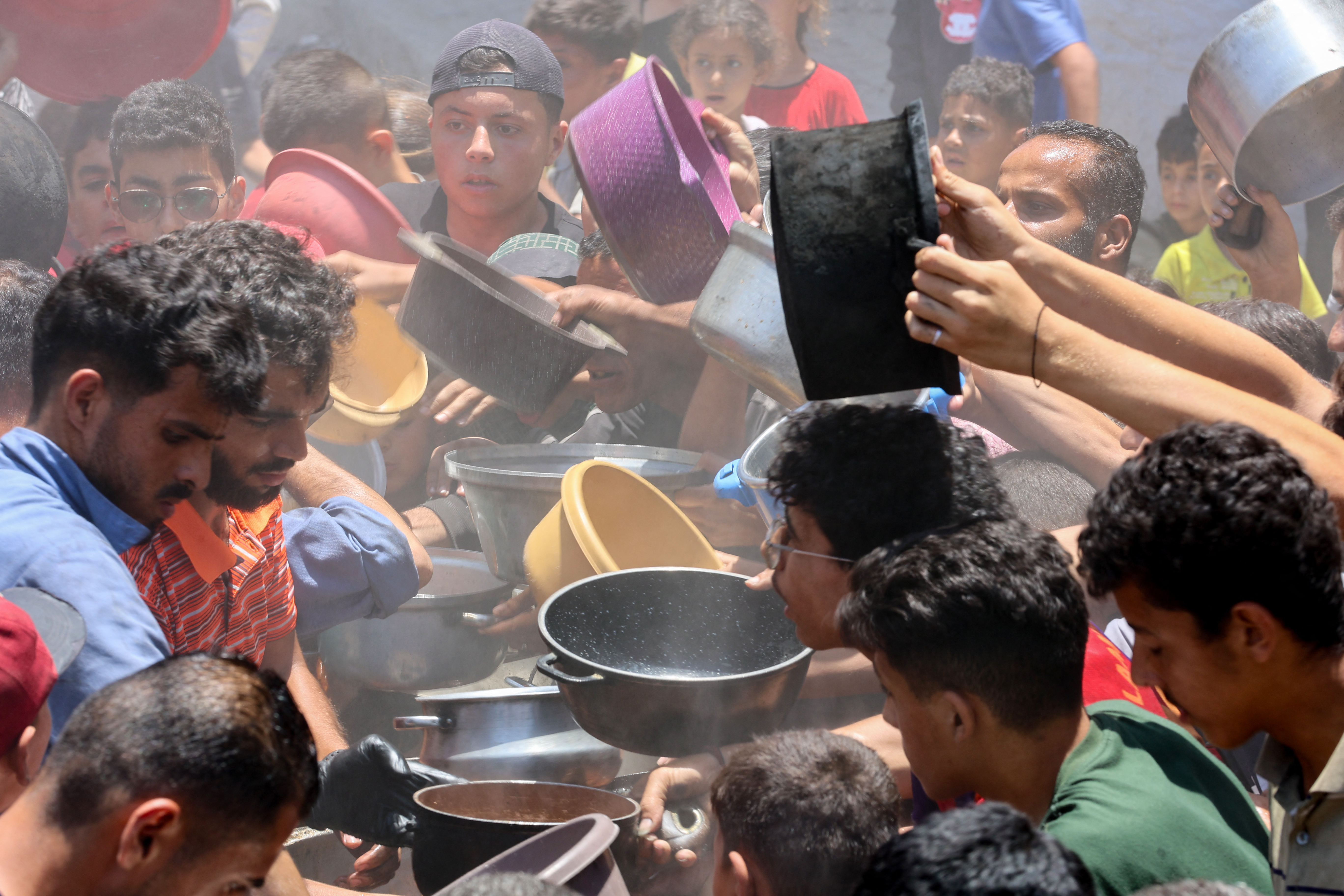 Palestinians try to get food at a charity kitchen providing hot meals in Rimal neighbourhood in Gaza City