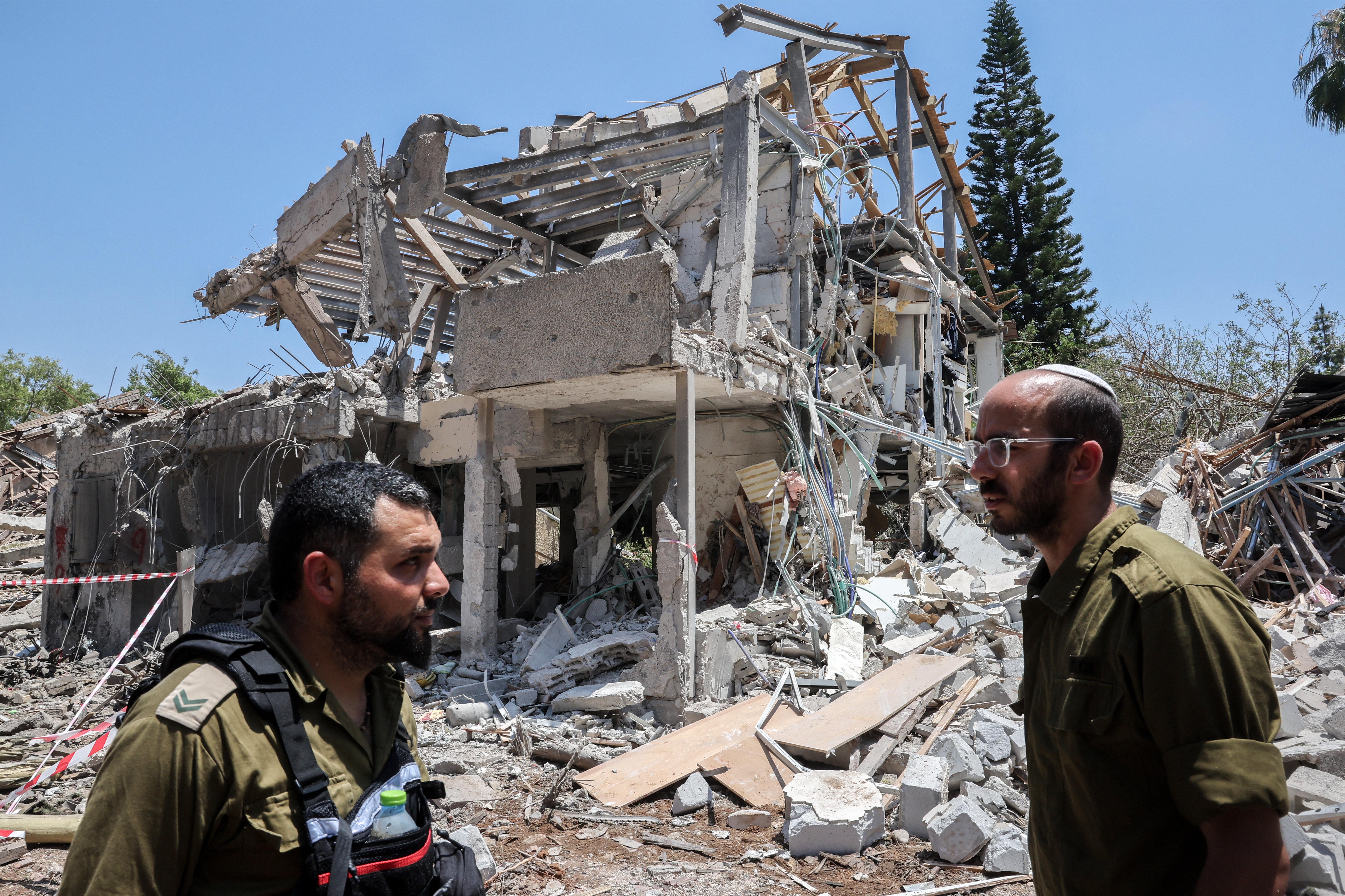 Israeli soldiers stand next to a destroyed house at the site of an Iranian strike that hit a residential neighbourhood in the Ramat Aviv