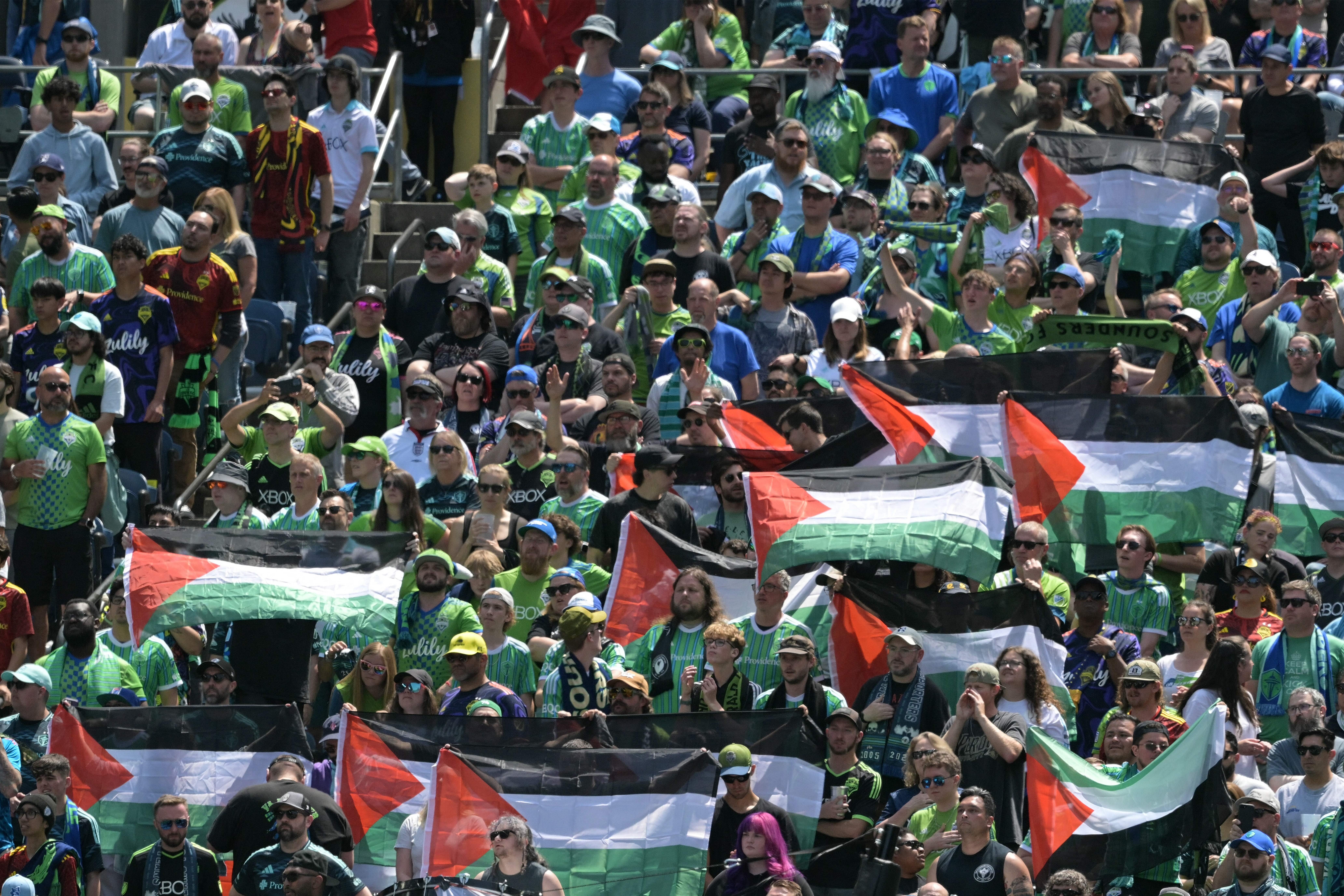 Fans of Seattle Sounders hold Palestinian flags during the FIFA Club World Cup 2025 Group B football match between US Seattle Sounders and France's Paris Saint-Germain at the Lumen Field stadium in Seattle on June 23, 2025. (Photo by JUAN MABROMATA / AFP)